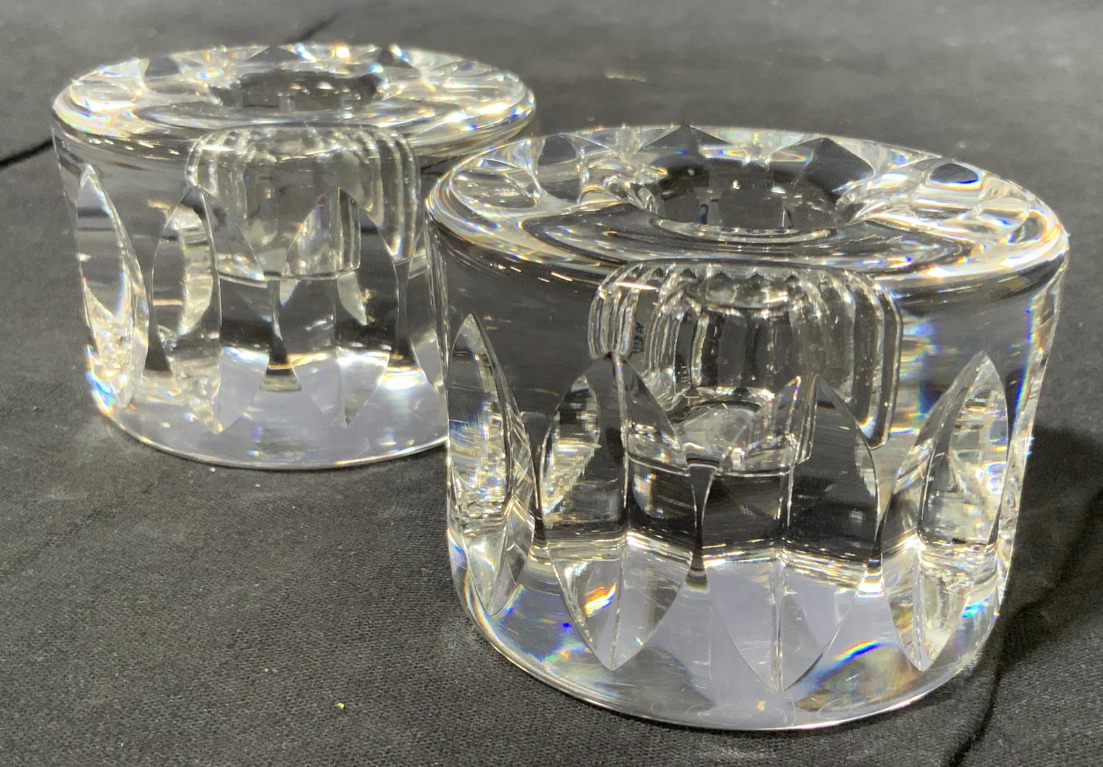 Pair of Orrefors Signed Crystal Candle Holders: A signed pair of vintage Orrefors Sweden crystal art glass candle holders. Each is signed underneath. The sides are faceted all around. Each measures approximately 2.75 inches in diameter and approxim