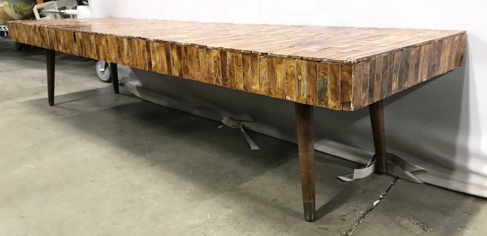 Low Mid Century Modern Tiled Coffee Table: Appears artist designed and artist crafted. Coffee table has splayed wooden legs. Table top appears to be porcelain tile. Table is mid century modern. Piece measures approximately 62 inches long 18 in
