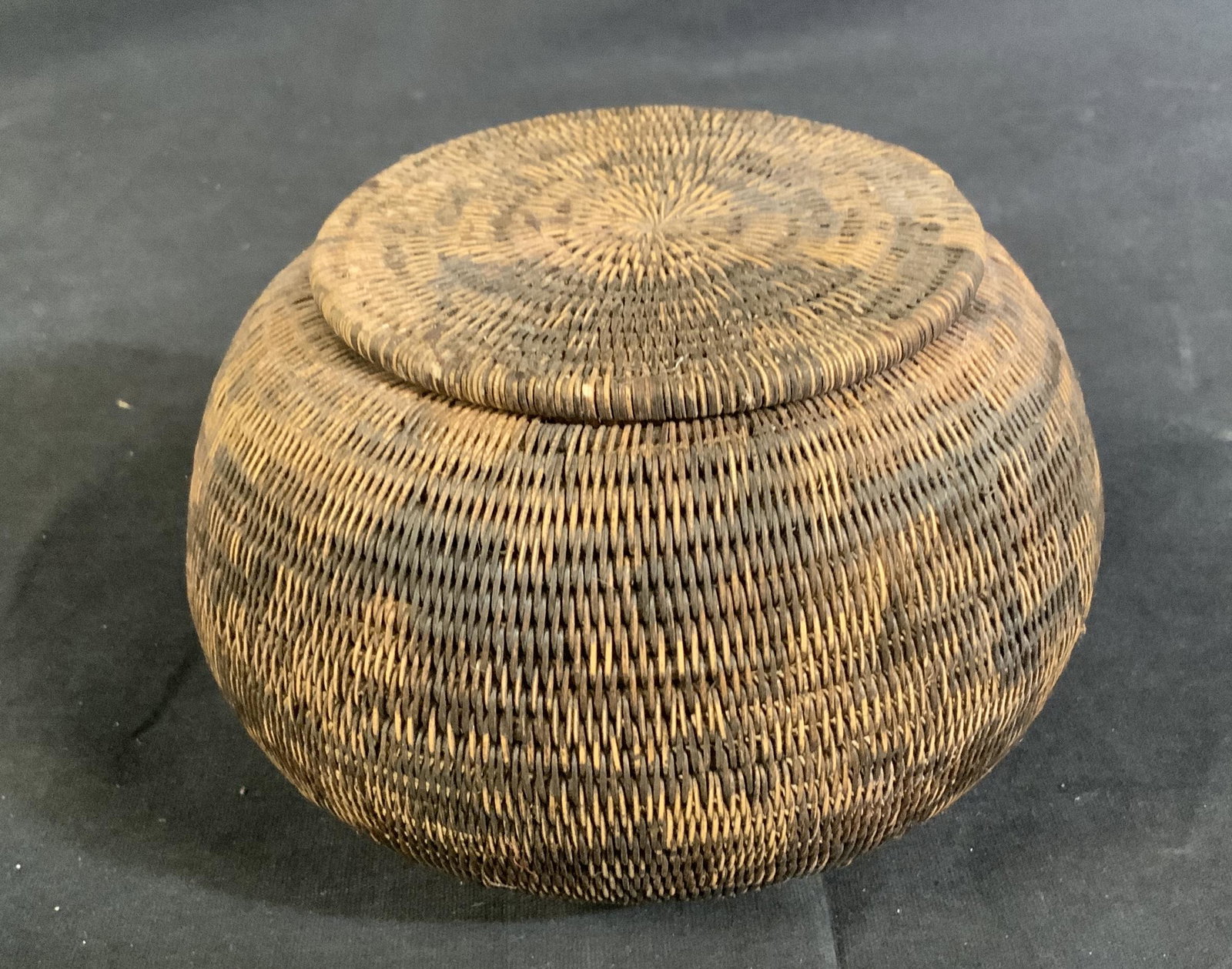 Woven straw Lidded Basket Box: Woven straw bowl with lid, no apparent inscriptions or stamps, woven brown straw, measures 6 inches in diameter at widest point x 3 3/4 inches tall, some pieces of straw are loose but overall in good 