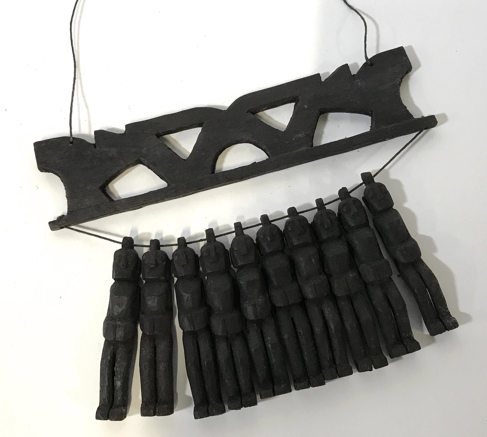 Far East Asian Wooden Hanging Sculpture: Far East Asian wooden hanging sculpture, sculpt depicts10 wooden figures hanging by a string through their heads said string attached wooden plaque, dark brown string holds up piece, measures 12 inche