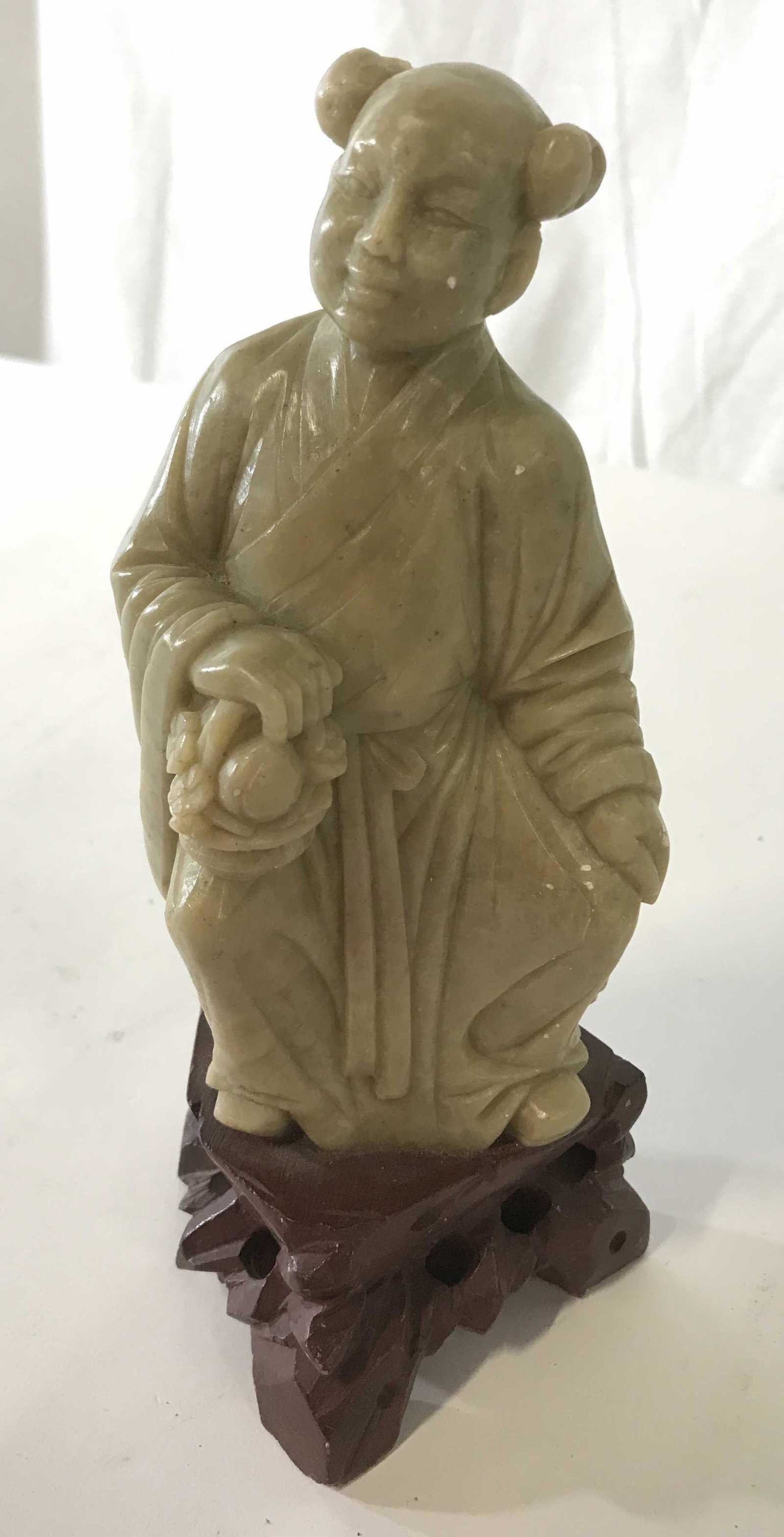 Asian Style Carved Stone Male Figure: Carved stone Figural, depicts a male figure carrying a basket of fruit and flowers. Measures approx 8 inches H and 4 inches W. Wear is consistent with age, some loss is present on piece. Orientalia, O