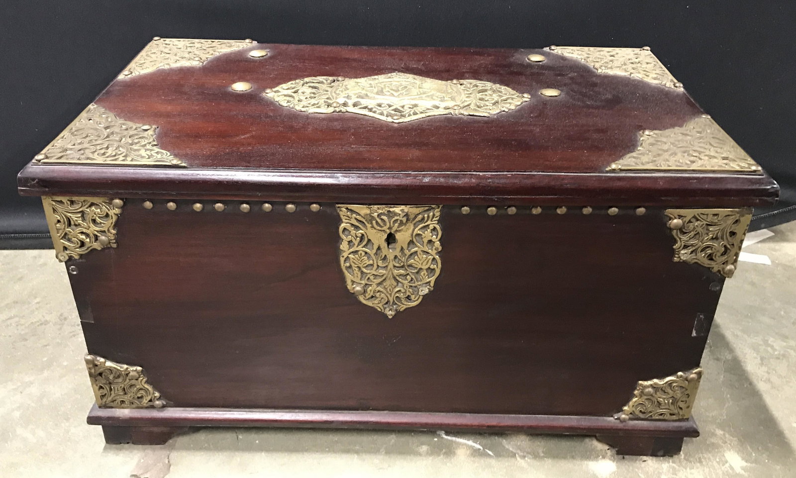 Vintage Wood Chest & Brass Detailing: Vintage wooden chest, possibly antique. Intricate brass detailing decorates corners of chest as well as the lid. Center of top is decorated with a coat of arms, a detailed brass lock can be found on t