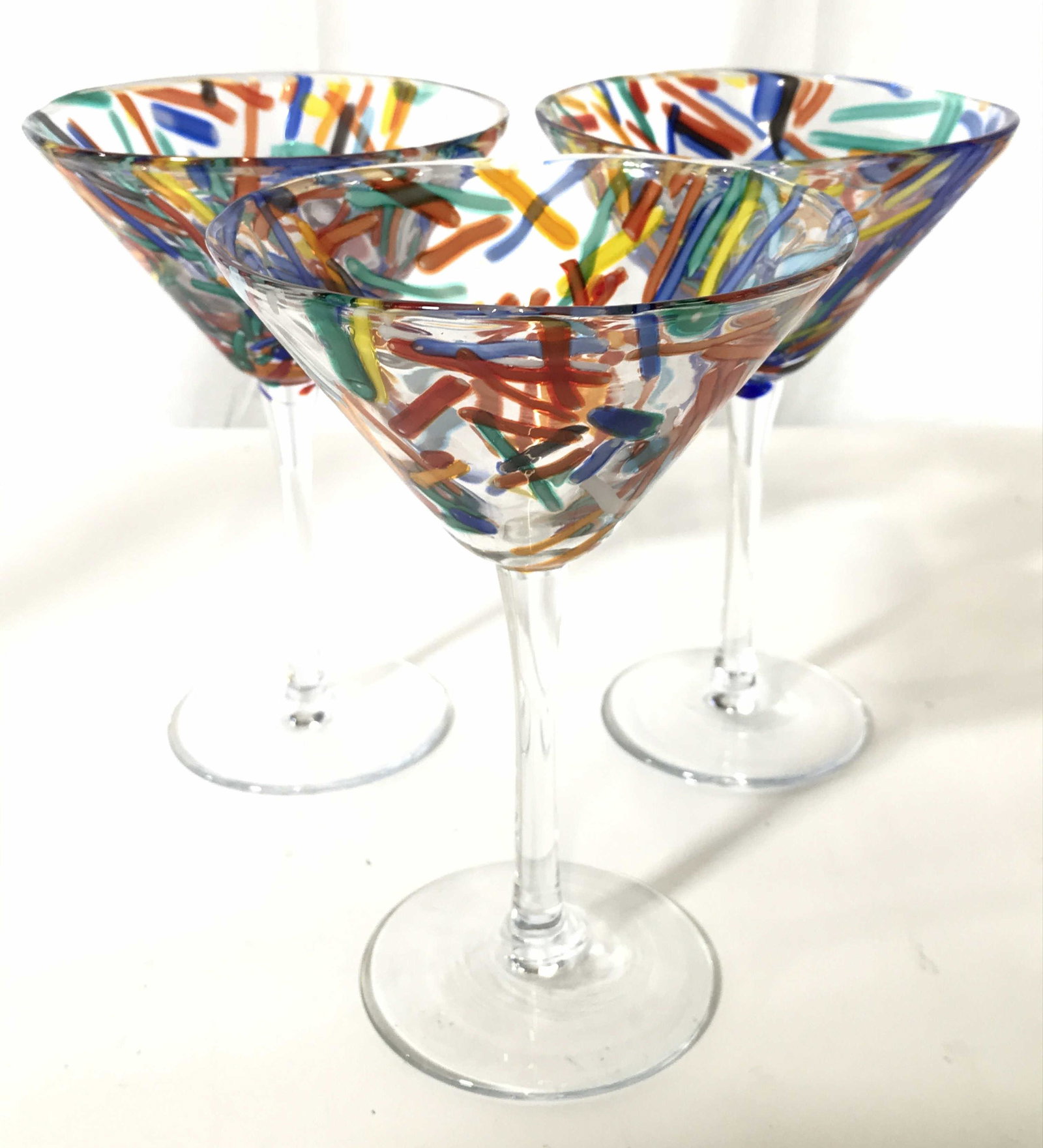 Set 4 Art Glass Martini Glasses: Lot includes 4 martini glasses. Each have multi toned detail around basin of pieces. Each measures approximately 7 inches tall 5 inches wide. Martini glasses, art glass, stemware, beverage ware, barwa