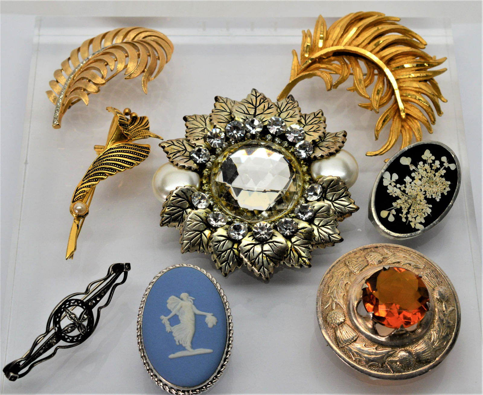 Lot of Eight (8) vintage brooches and pendants: 8 in all including Trifari feather w cubic zirconia, wedgwood in sterling, gold-plated tiger lily w pearl, feather brooch, rough orange topaz in sterling made in Great Britiain, vintage sterling pin w