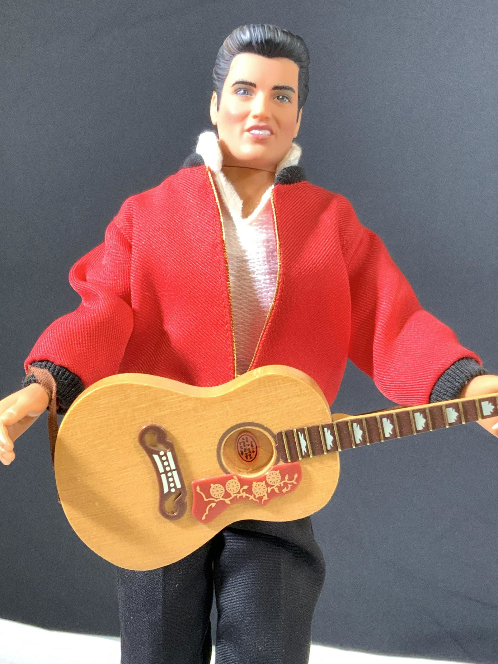 Collectible Standing ELVIS Doll: Elvis doll holding guitar on doll stand, embossed signature reads: Elvis Presley. Underside states ‘Elvis Presley Enterprise Inc.’ Doll has moveable legs and arms. Crisp white shoes. Stand is 7 by