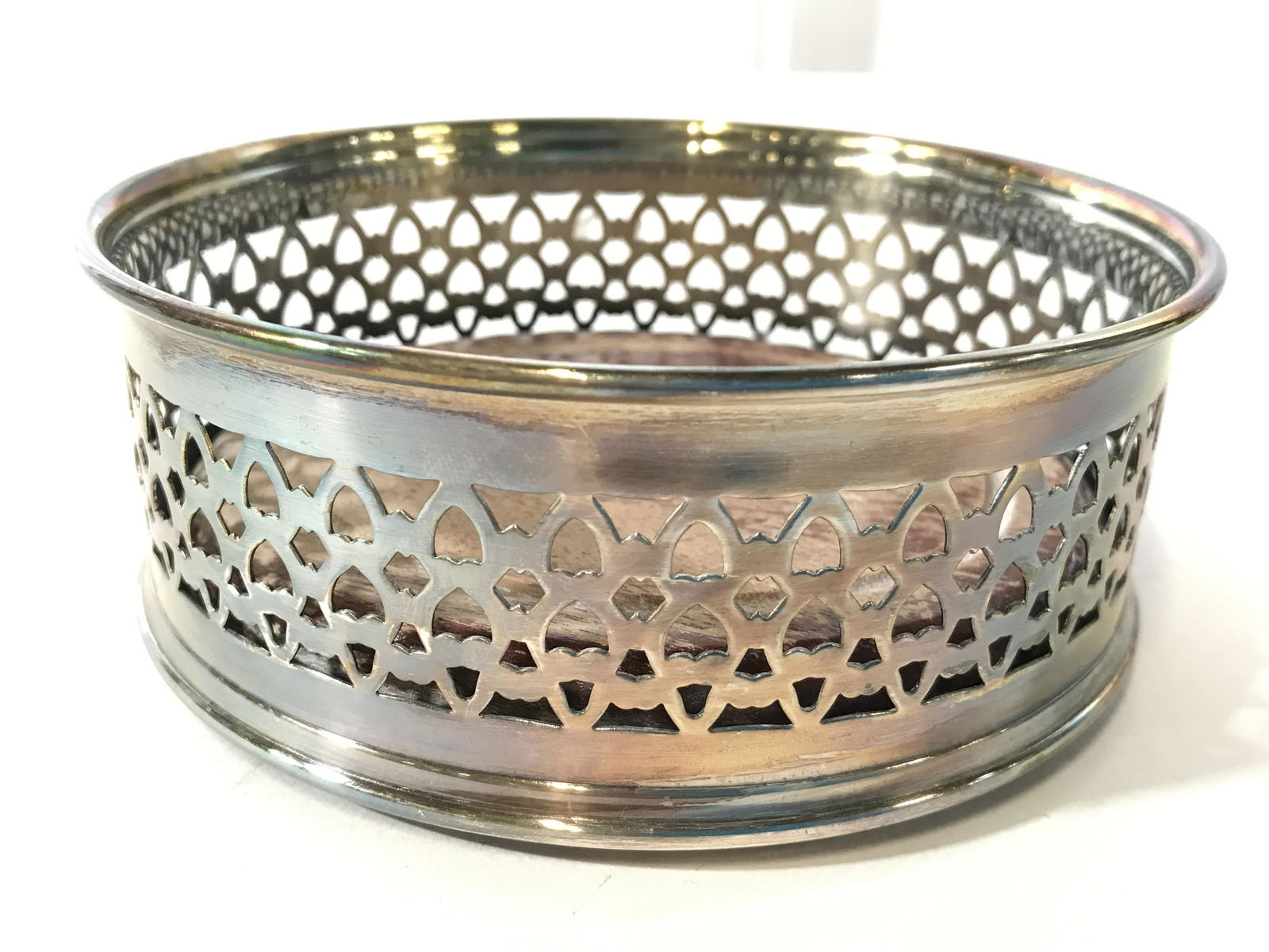 Lot 2 Silver Toned Metal Wine Coasters: Lot includes 2 wine bottle coasters. Each are silver toned and metal. One has pierced detail the other has grape, vine and leaf relief detail. Largest piece measures approximately 5.25 inches wide, 2