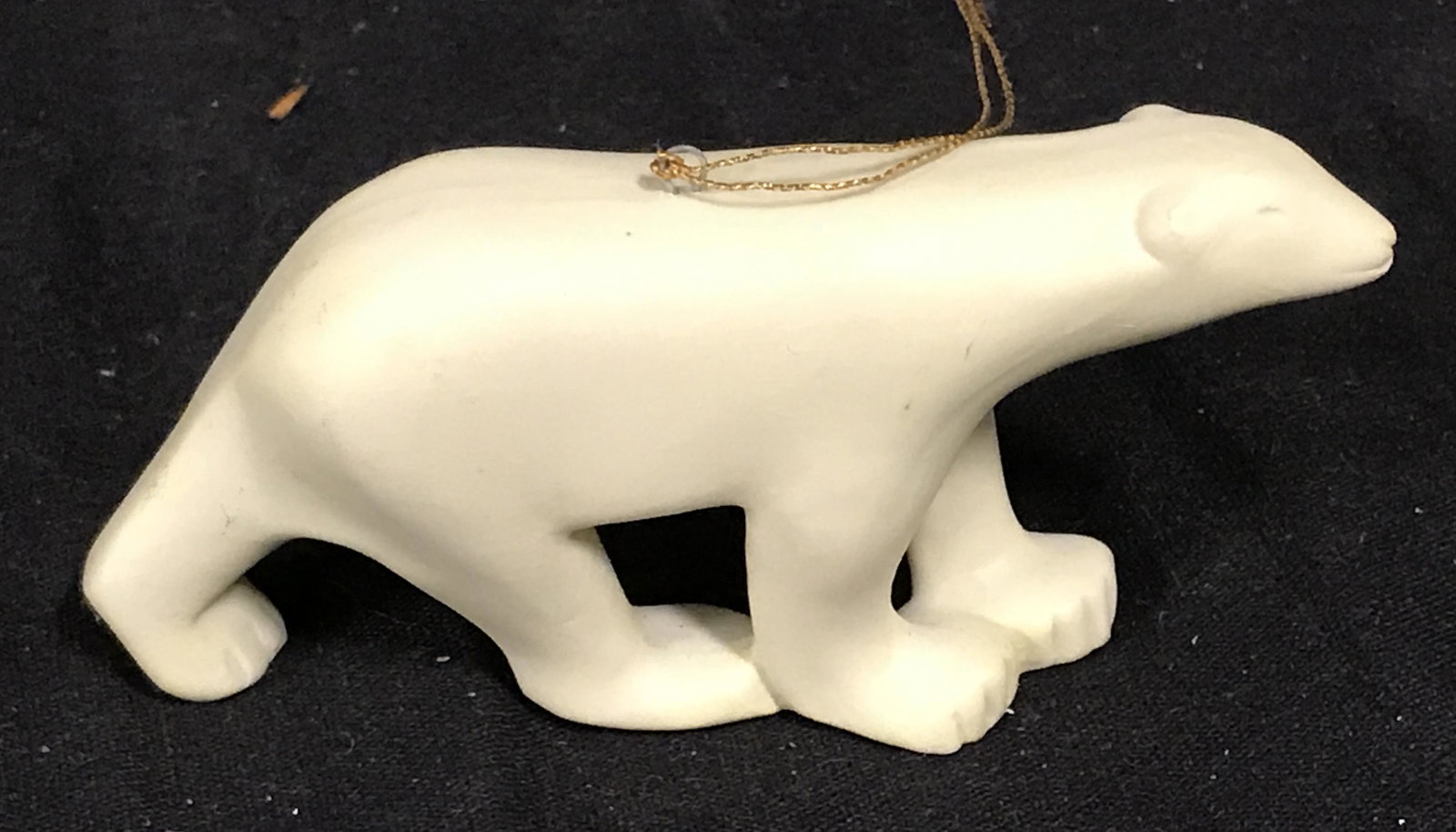 Porcelain Polar Bear Ornament: Porcelain polar bear ornament, minimalist polar bear with a gold colored chord, sticker residue to underside, measures 4.25 inches long and 2 inches tall, some scuffs to surface, Side of leg reads MMA