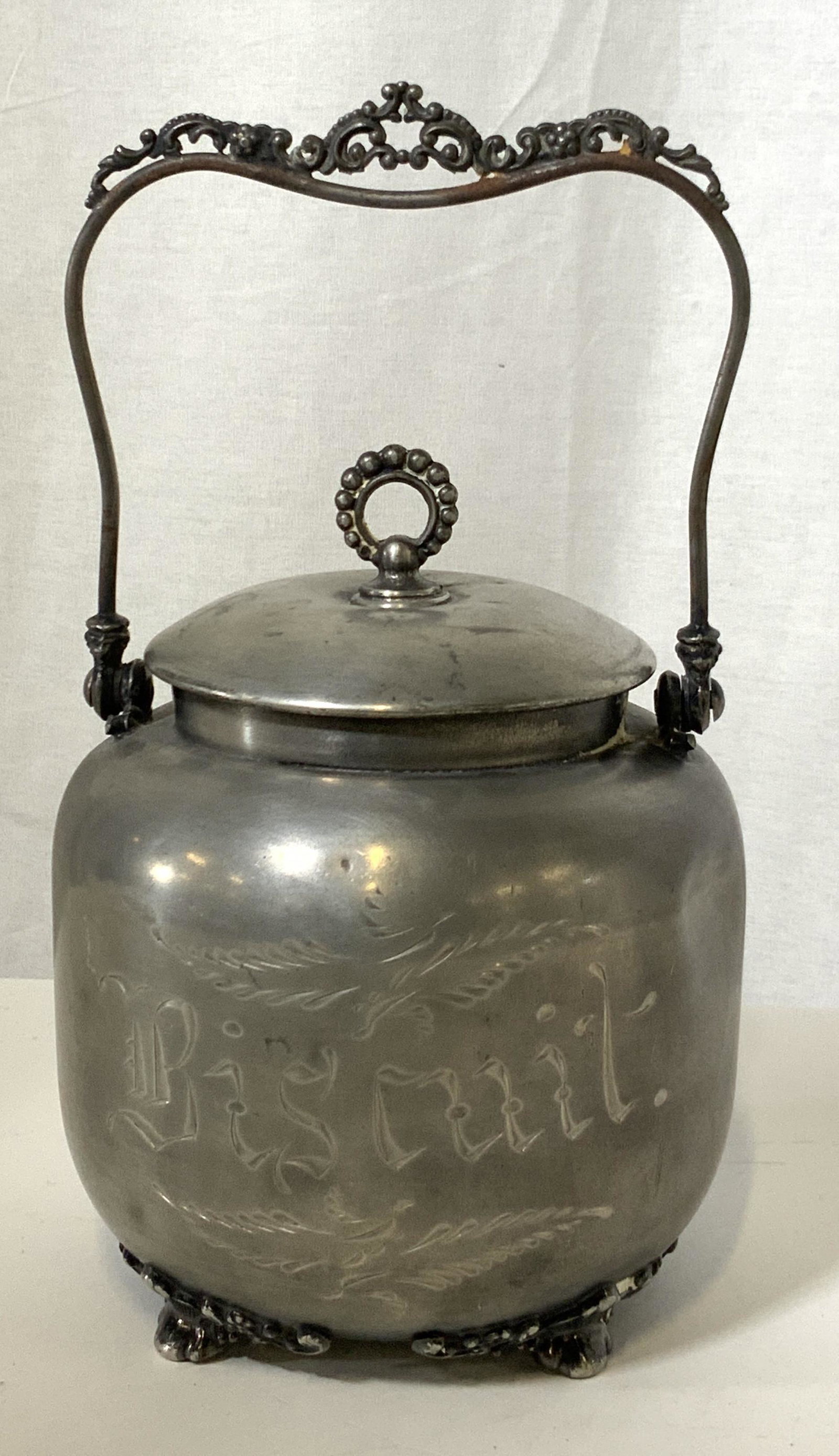 Vintage Silver Plated Biscuit Jar, CANADA: Vintage silver plated biscuit jar. Underside reads: EPBM ‘WR’ Canada 972. EPBM stands for electroplated Britannia Metal. Underside of vessel has decorative feet. Front reads: Biscuit. In good vint