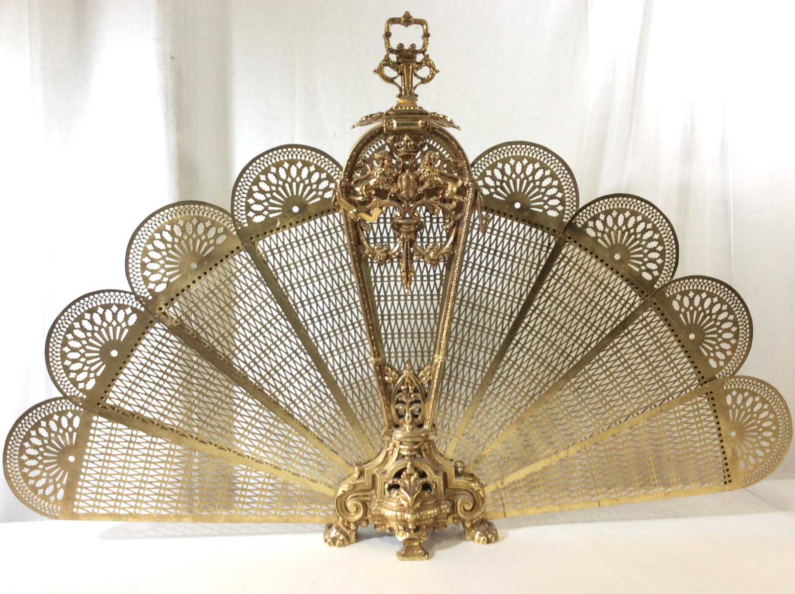 Brass Peacock Victorian Style Fireplace Fan Screen: Elaborate brass Peacock fan that goes in front of fireplace. Blades slide out from sides, flanking Center Stand. Royal lions flank shield in design. Footed claw design. Pierced metal. Victorian Style.