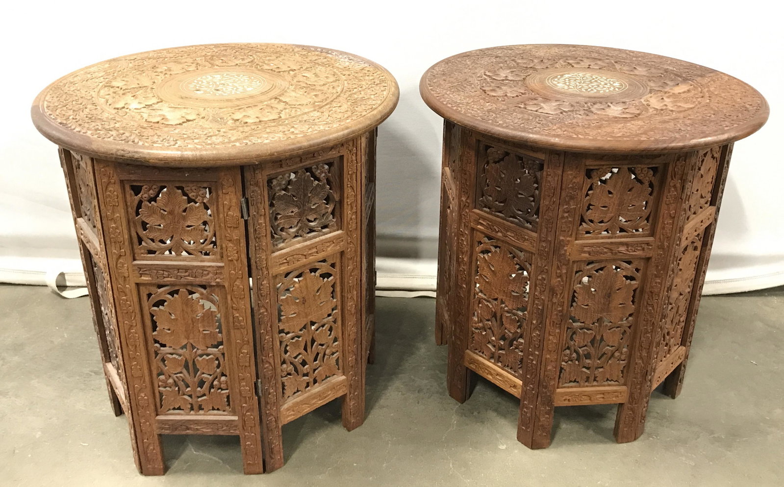 Pair Carved Wood Indian Style Side Tables: Pair vintage carved wood tables. Table bases are octagonal and collapsible. Table top is intricately detailed, center is decorated with leaf like detailing, detailing is inlaid. Tabletops are removabl