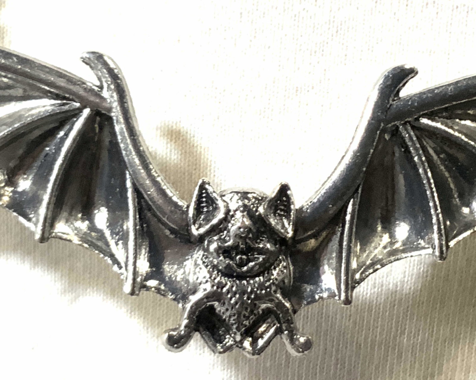Silver Toned Large Bat Figural Necklace: Adjustable silver toned necklace depicting repousse bat in flight. lobster clasp, chain attached to Center pendant. Statement piece for Halloween or party. Chain approx. 28 in. + L Pendant approx. 4.5