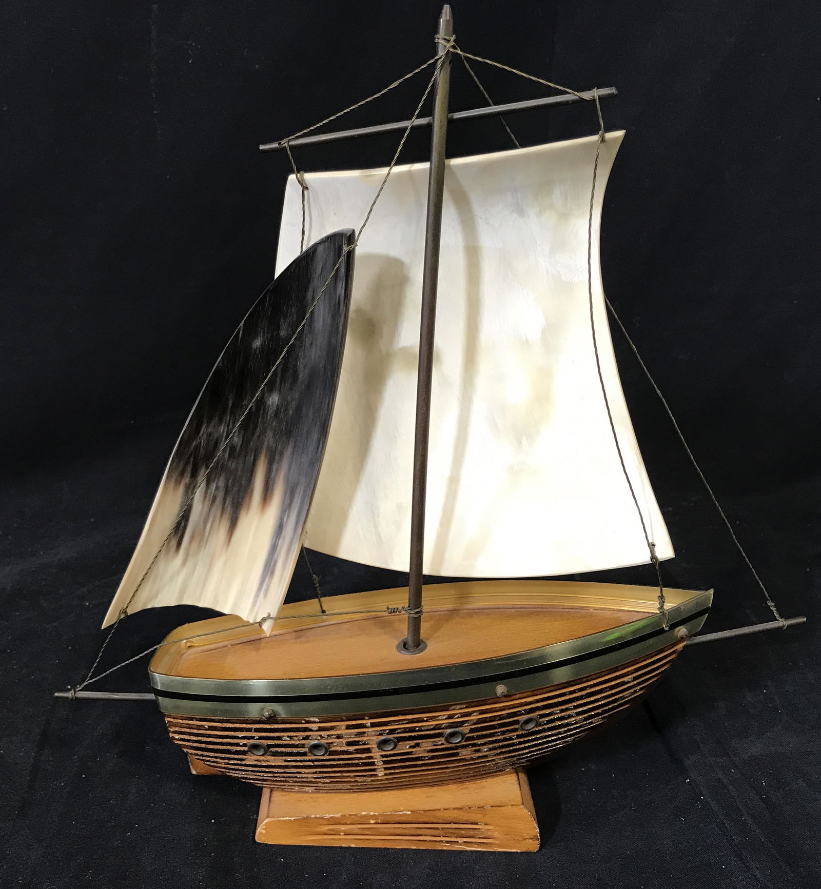 Mixed Materials Ship Model Decorative Accessory: Model ship made of wood with metal embellishments wire and sails made of resin, seated on a wooden platform, platform measures 4.25 inches by 2.25 inches, ship measures 11.5 inches at widest point and