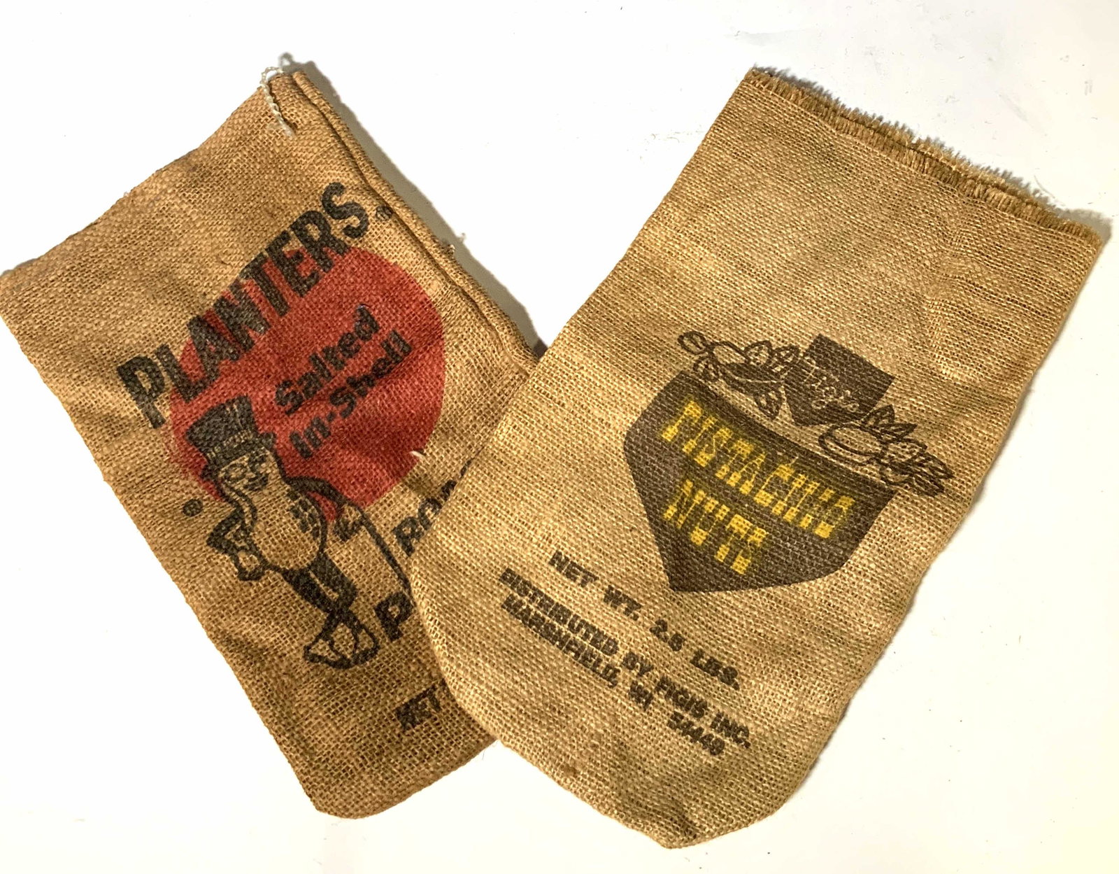 Lot 2 Collectible Vintage Burlap Sacks, PLANTERS: 2 collectible burlap sacks. Once were pistachio and peanut sacks. collectible farmhouse decor. Peanut sack reads: Planters, Salted in Shell, Roasted Peanuts. Includes mascot, Mr. Peanut. Pistachio sac