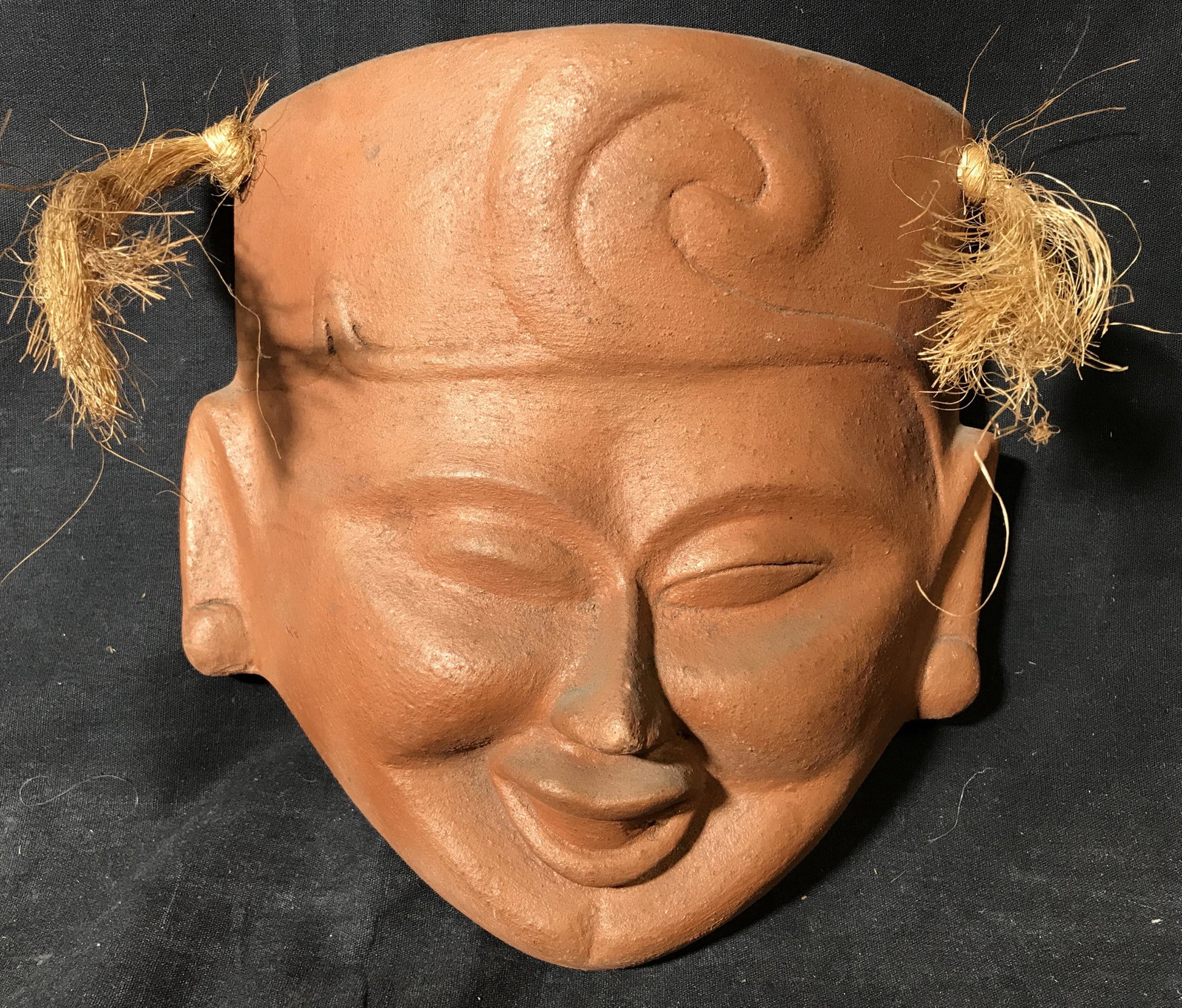 Decorative Earthenware Mask: Decorative earthenware mask, possibly vintage, possibly antique. Depicts a hatted figure, braided roped allows for wall mounting. Measures approx 9.5 inches H, and 8.5 inches W. Wear is consistent wit