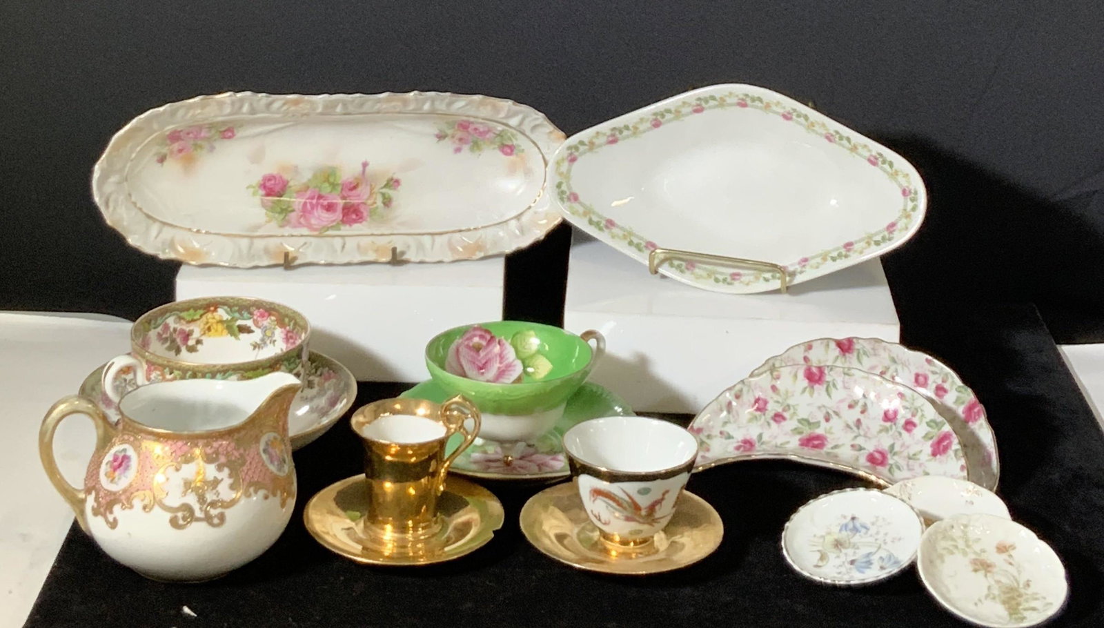 Lot 16 Assorted Ceramic & Porcelain Kitchenware: Assortment includes: cups (4), trinket dishes/teabag holders (3), saucers (4), crescent plates (2), serving dishes (2), milk jug/vessel (1). Assortment features floral designs, gilt line work, & drago