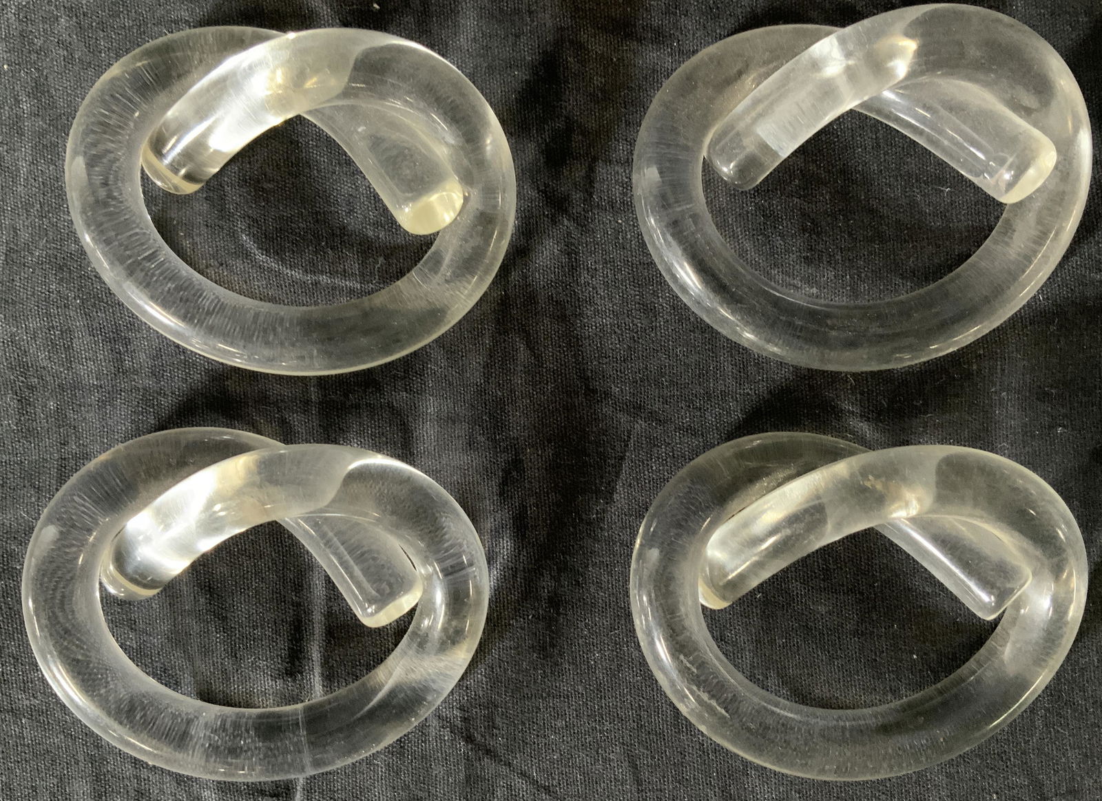 Lot 4 Vintage Lucite Napkin Rings: Lot 4 Vintage Lucite Napkin Rings, no apparent or inscriptions, possibly Dorothy Thorpe, twisted pretzel like design, All measure 2 1/8 x 3 inches, some wear from use but overall in good condition, Se