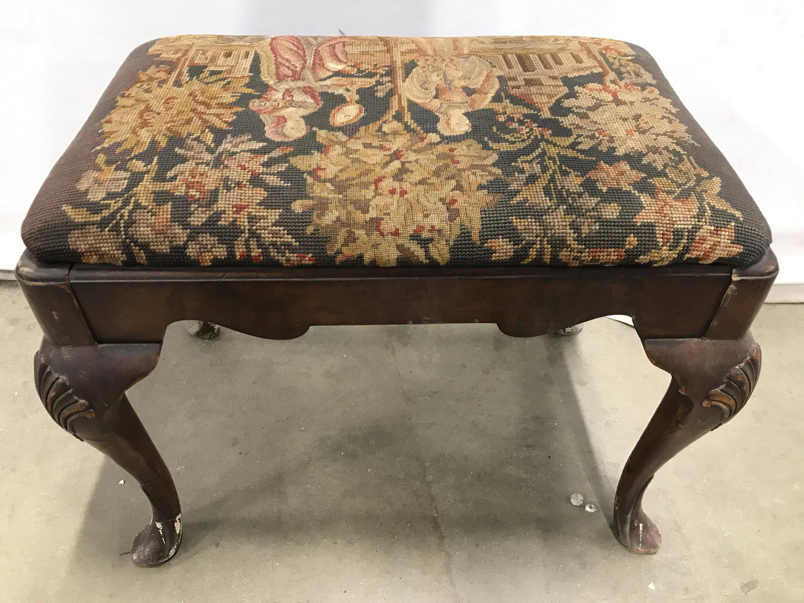 Vintage Needlepoint Cabriolet Leg Footstool: Piece is vintage. Contains needlepoint upholstery with depiction of 2 figures. Footstool, needlepoint footstool, bench, cabriolet leg footstool, upholstered footstool, vintage footstool, needlepoint b