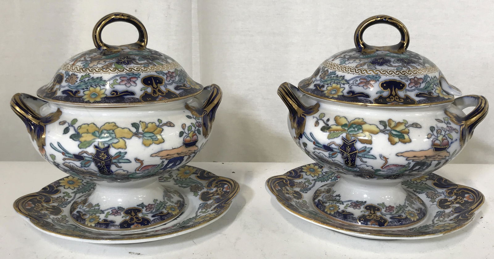 Pair Porcelain Floral Lidded Dishes & Plates: Pair porcelain floral lidded dishes and plates, both have lids with divots in them for serving utensils, interior of lids have labels that read ‘A65567 2-B’ same Labels to the underside of the bow