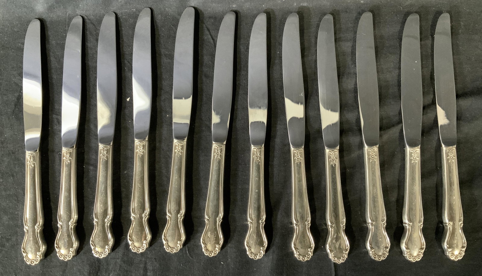 Set 12 Sterling Silver Knife Set: Lot 12 stainless steel & sterling silver knives, sterling handled knife set, stainless blades, sterling place settings, sterling silver tableware. inscription to blades reads ‘stainless’, Inscript