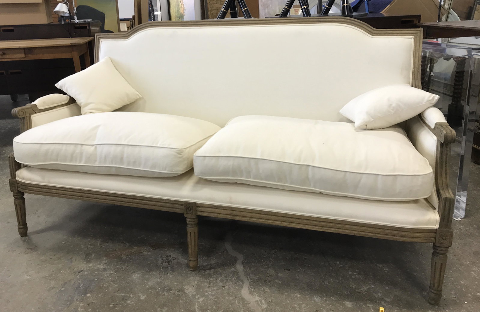 Vintage Bergere Style Sofa: Bergere style sofa. Vintage, possibly antique. Frame is carved wood, upholstery is cream toned. Upholstery secured to frame is double welted. Carved detailing is present on arms and back, legs are flu