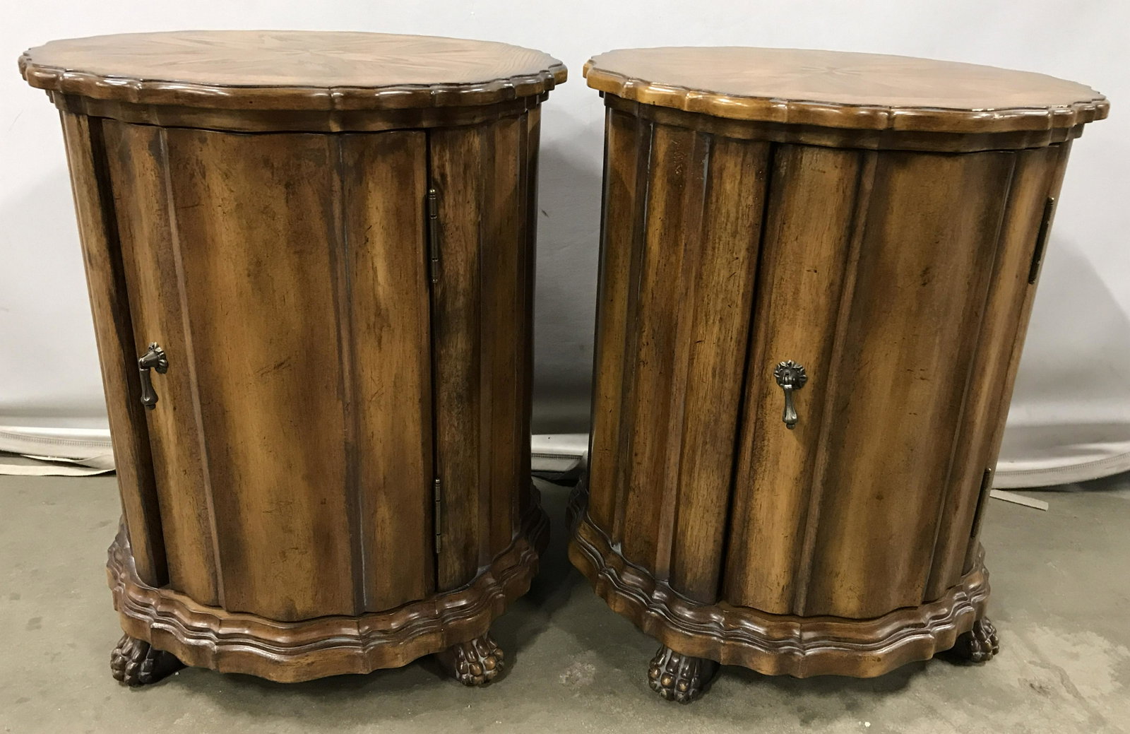 Pair Wooden BUTLER SPECIALTY Side Table Cabinets: Pair of side table cabinets, crafted from carved wood, possibly vintage. Cabinets are footed, each foot is carved and depicts a paw. Door pulls appear to be brass. Label on underside reads as BUTLER S
