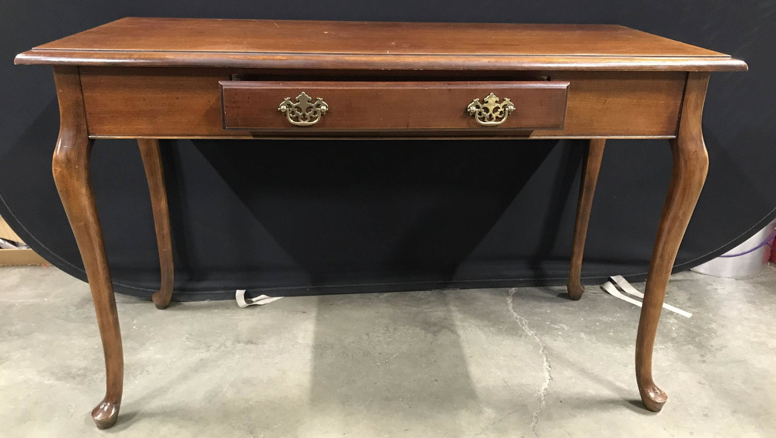 Vintage Wooden Cabriole Leg Console Table: Console table is vintage and wooden. Piece has 4 carved cabriole style legs. Table has drawer with gold toned metal handle and hand dovetailing. Console table measures approximately 49 inches long 30 