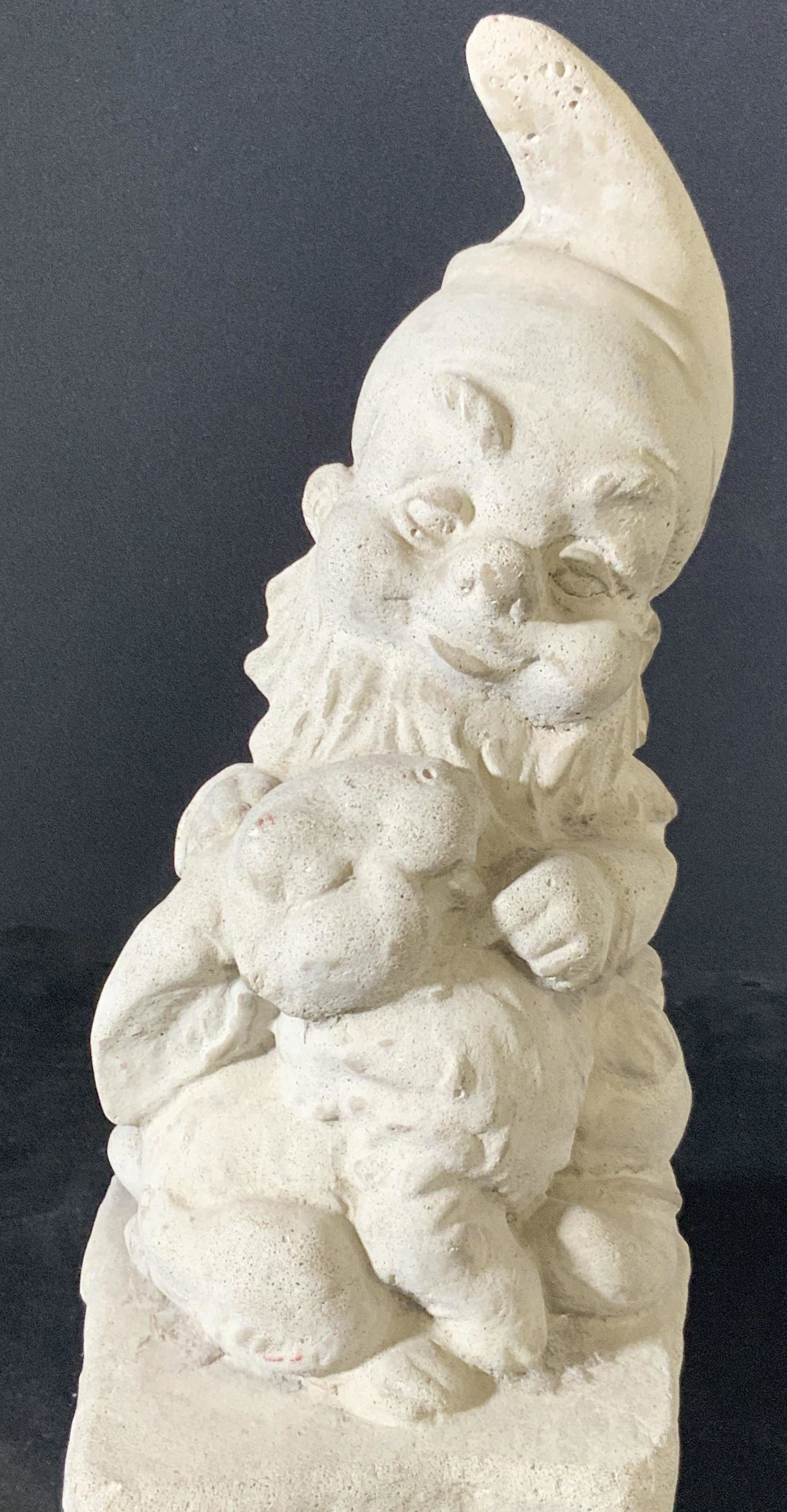 Cement Garden Gnome & Rabbit Statue: Cement mold statue depicting a smiling garden gnome, sitting atop a mushroom, petting a rabbit. Weighted Object. Approx. 4 in. width. Approx. 13 in. height. Garden gnome statue, cement statue, rabbit 