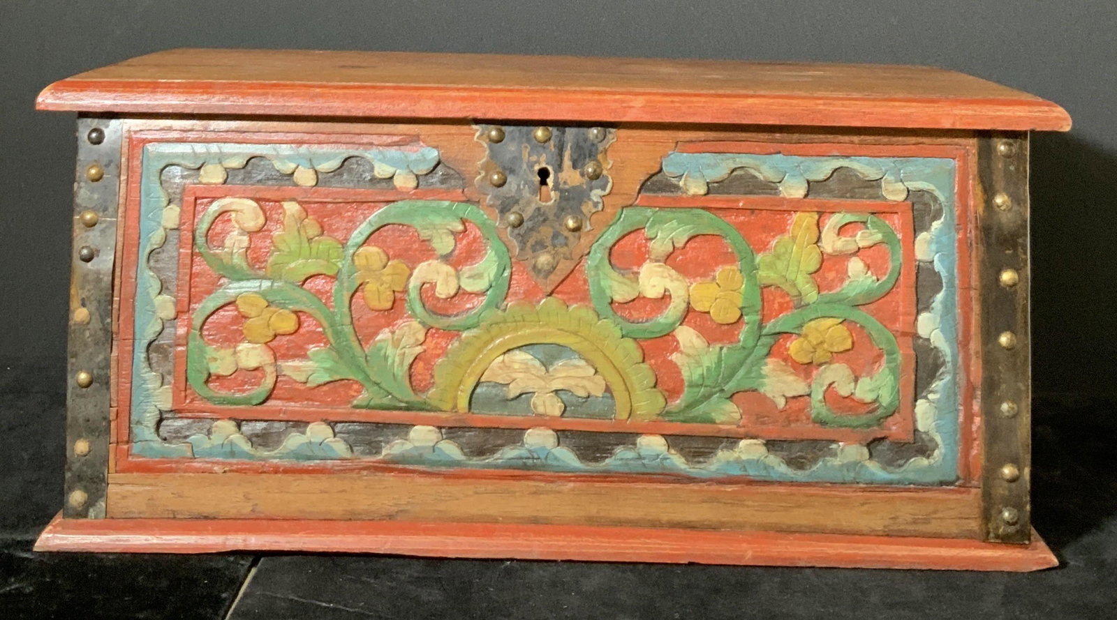 Decorative Antique Hand Painted & Carved Box: Folk Art Wooden box with carved designs painted reds, greens, and blues. Carved scene depicts nature motifs. Lidded box. Metal hardware along sides and metal hinges & handles. Interior of box contains