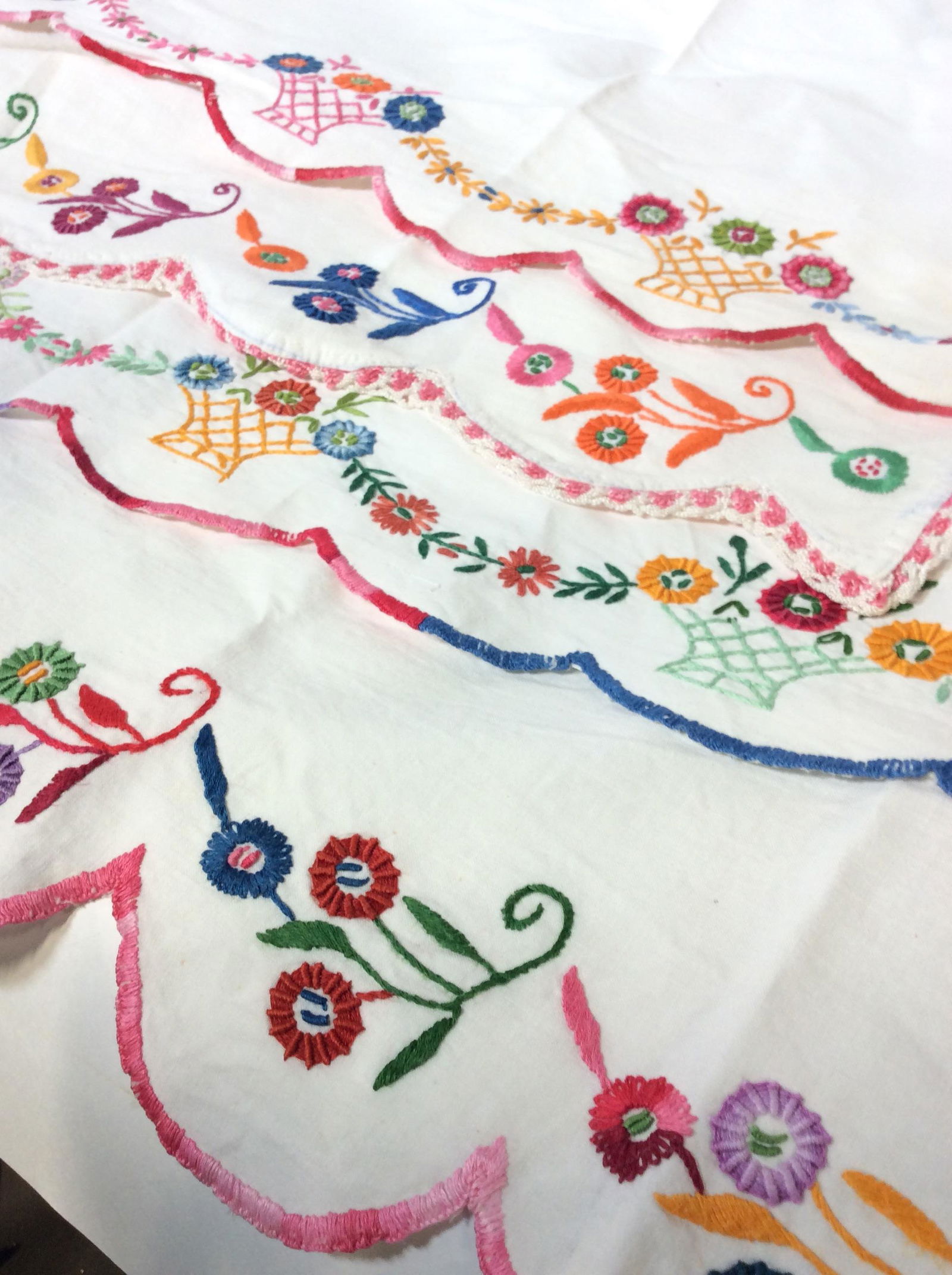 Vntg Collectible Embroidered Table Linens: Lot consists of 2 matching embroidered linen table runners on beige linen with red hand embroidered flowers (13.5 x 45 in), center table runner with large embroidered flowers, crochet rim. Several Emb