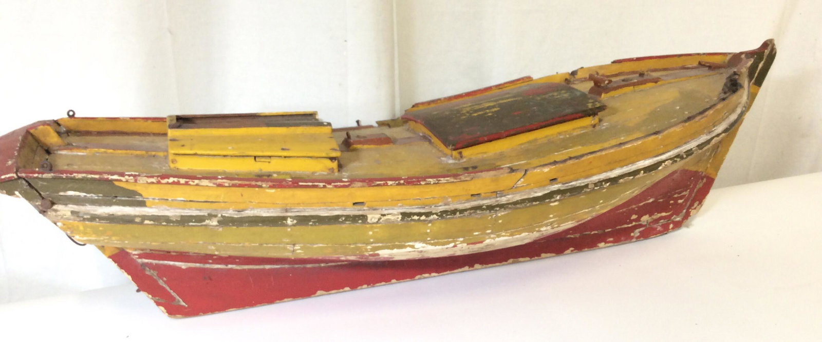 Oversized Painted Antique Wood Boat Model: App 34.5 in long, 13.5 in wide, 9.25 in ht. Handmade antique boat, fishing vessel, compartments, will need extra screw eyes on bow to hang. Painted yellow and red. Peeling paint and wood cracking cons