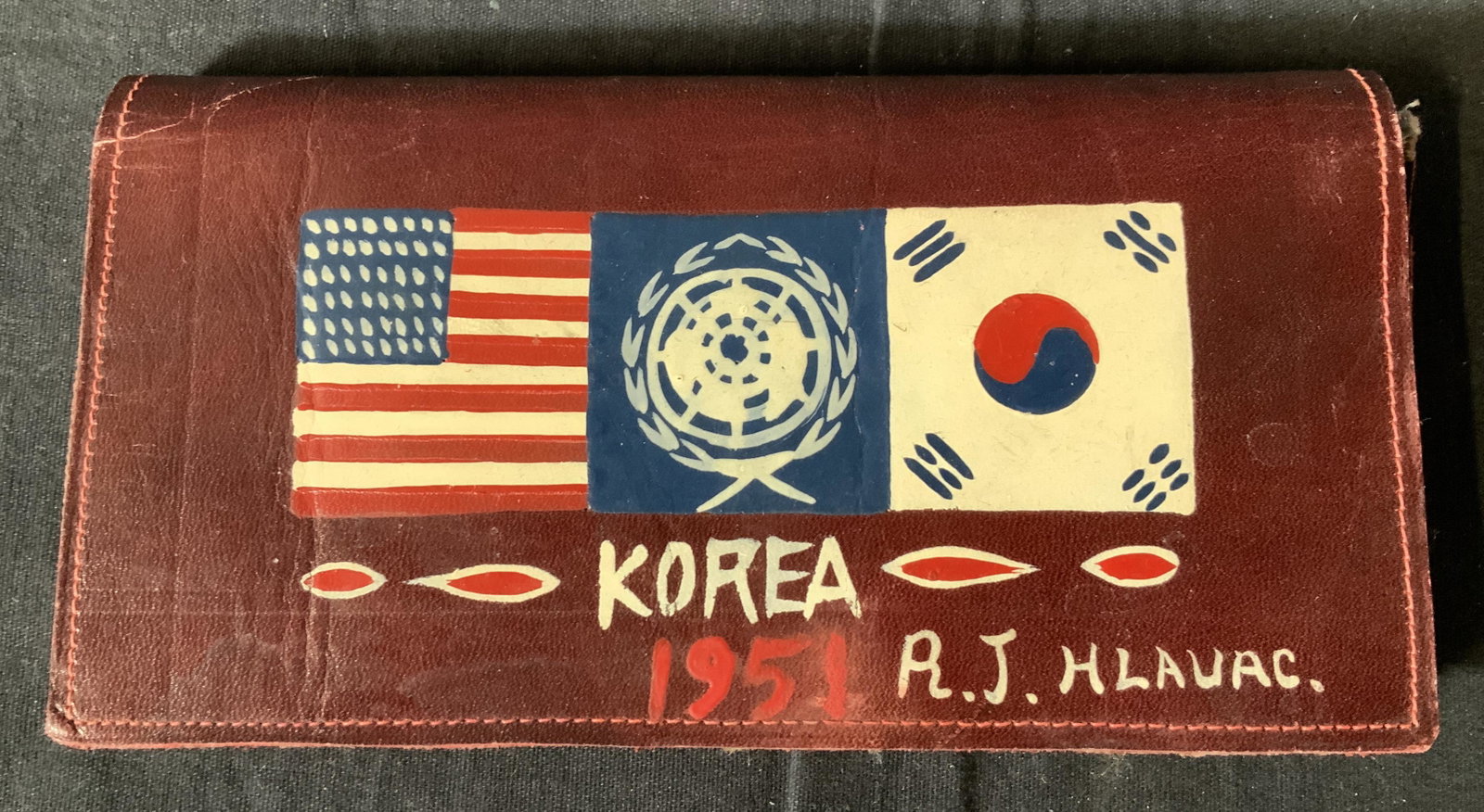 Vintage Men’s Wallet: Vintage men’s wallet, inscription to wallet reads ‘Korea 1951 RJ Hlauac’, painted American and Korean flags as well as UN logo, measures 3 5/8 x 7 1/8 inches, wallet has wear to exterior, inner 