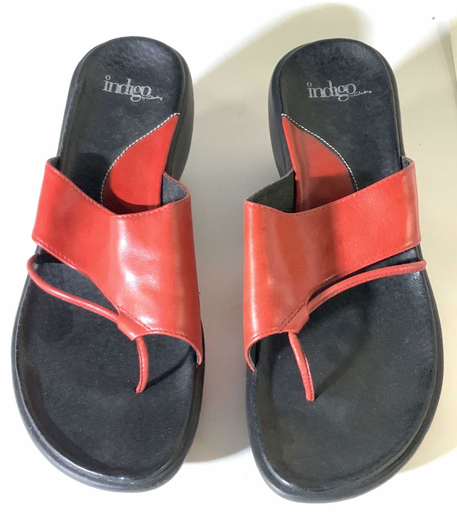 CLARKS Red & Black Leather Heeled Sandals: Indigo by Clarks leather wedge heeled sandals. Red strap, black and red sole. Interior of strap reads: 34238 9M 12/03, Made in China 26, Leather Upper, Balance Man Made. Underside reads: Indigo. Size: