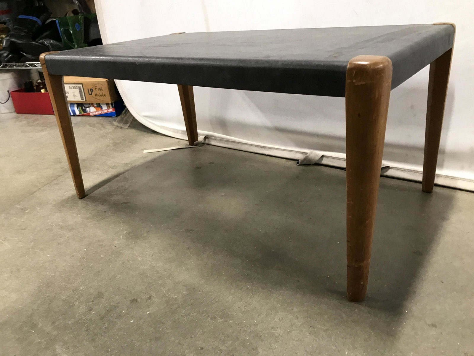 Leather Top Wooden Coffee Table: Coffee table has slate toned top which appears to possibly be leather. Table structure is wooden. Piece measures approximately 32 inches long 15 inches tall 19 inches deep. Table, coffee table, wooden