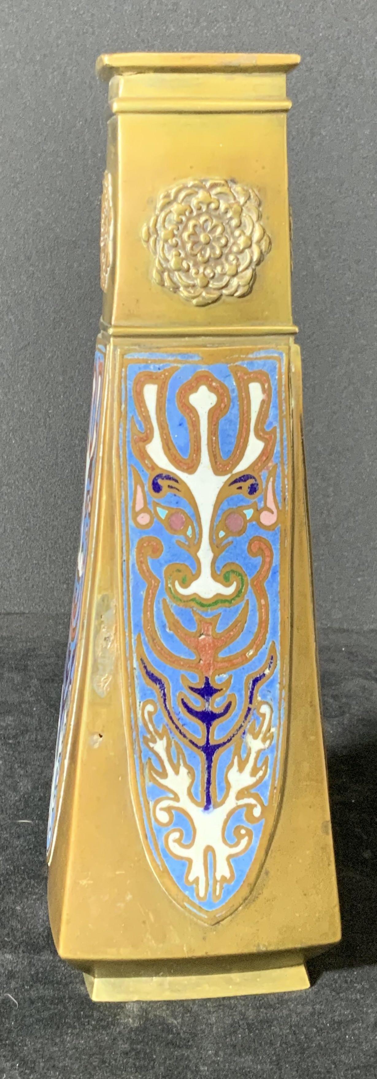 Decorative Dragon Champlevé Metal Vase: Metal, possibly brass, vase with champlevé inlay & embossed metal floral designs. Inlay colors include: blues, greens, white, pinks. Appears to be depicting a dragon. Weighted piece. Approx. 9.5 in.