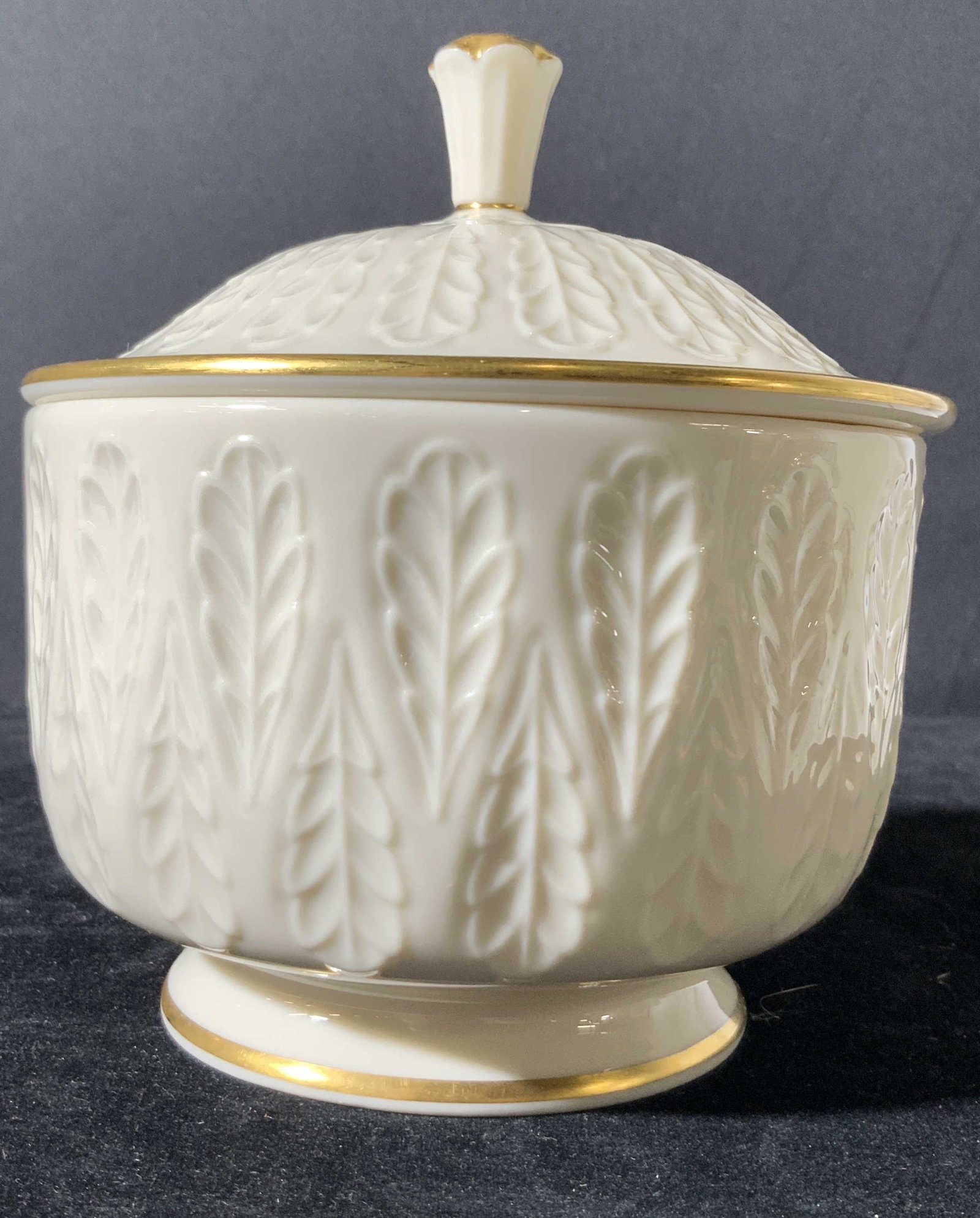 Signed Lenox White Porcelain Lidded Bowl: White porcelain lidded bowl w/ gilt line work. Embossed leaves / feathers throughout lid & bowl. Vessel for storing sugar, trinkets, & more. Underside stamped: Lenox Made in USA. Approx. 6 in. height 