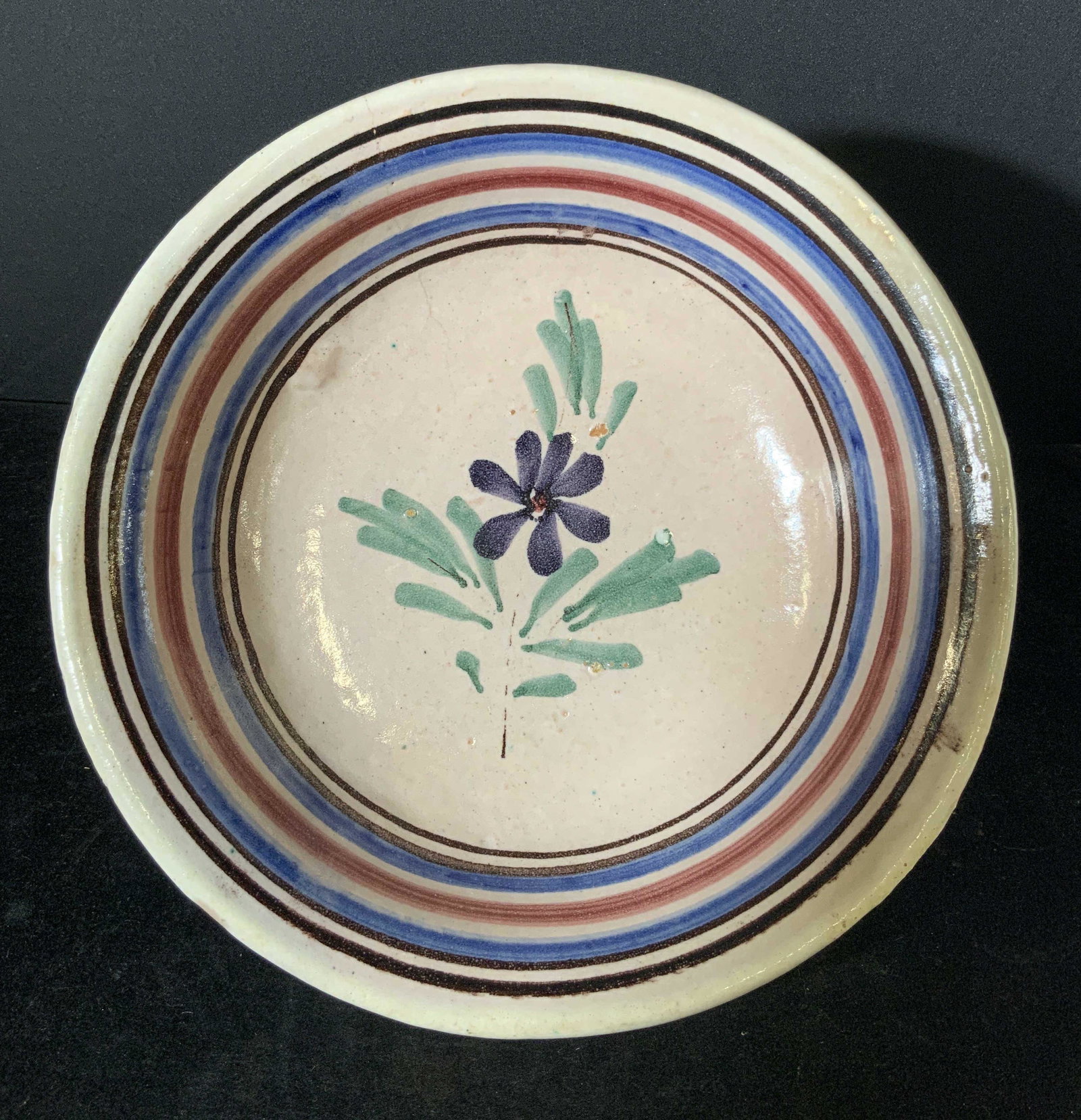 Handmade Ceramic Glazed Centerpiece Bowl: Possibly vintage (some pitting) thick-walled ceramic glazed bowl with hand painted floral design in the center. Blue, red, and dark brown banding along inner rim. Mild bubbles & cracks due to age and 