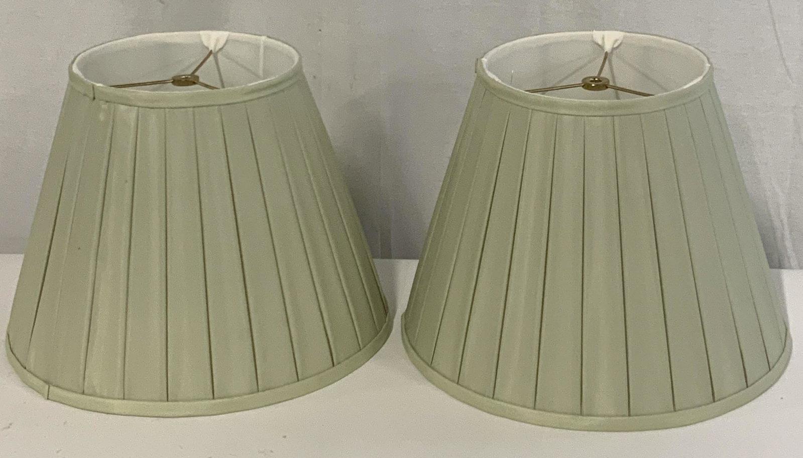 Pair Pleated Green Silk Lampshades: Pair of Empire style pleated lampshades from ‘ The Accessory Shop ‘ in Stamford, CT. Material: Silk. Color: Light Green. Approx. 12 in. height. Approx. 17 in. width. Lamp Shade, lighting accessory