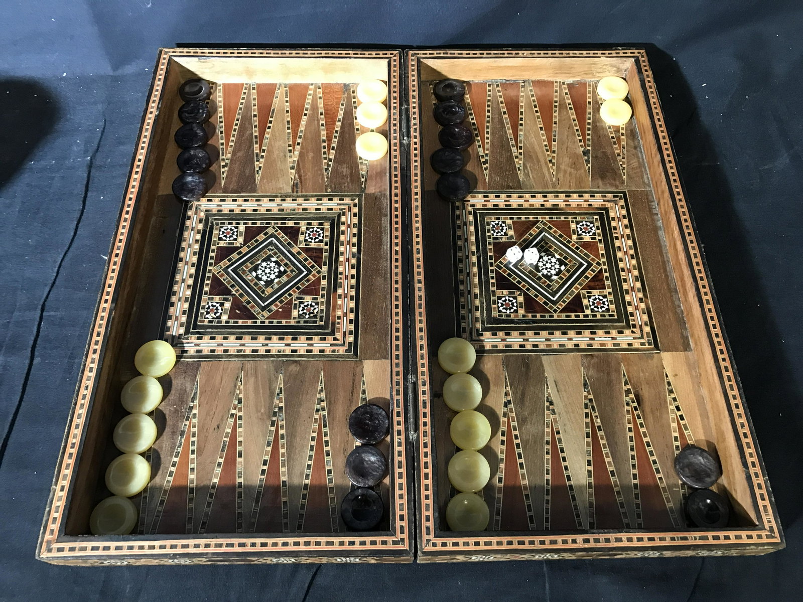 Vintage Multi Toned Wooden Backgammon Set: Vintage wooden backgammon table. Multi toned wooden inlays produce geometric patterns. Board can collapse fro storage and transportation. Included 30 play pieces, and a pair of dice. Largest piece mea