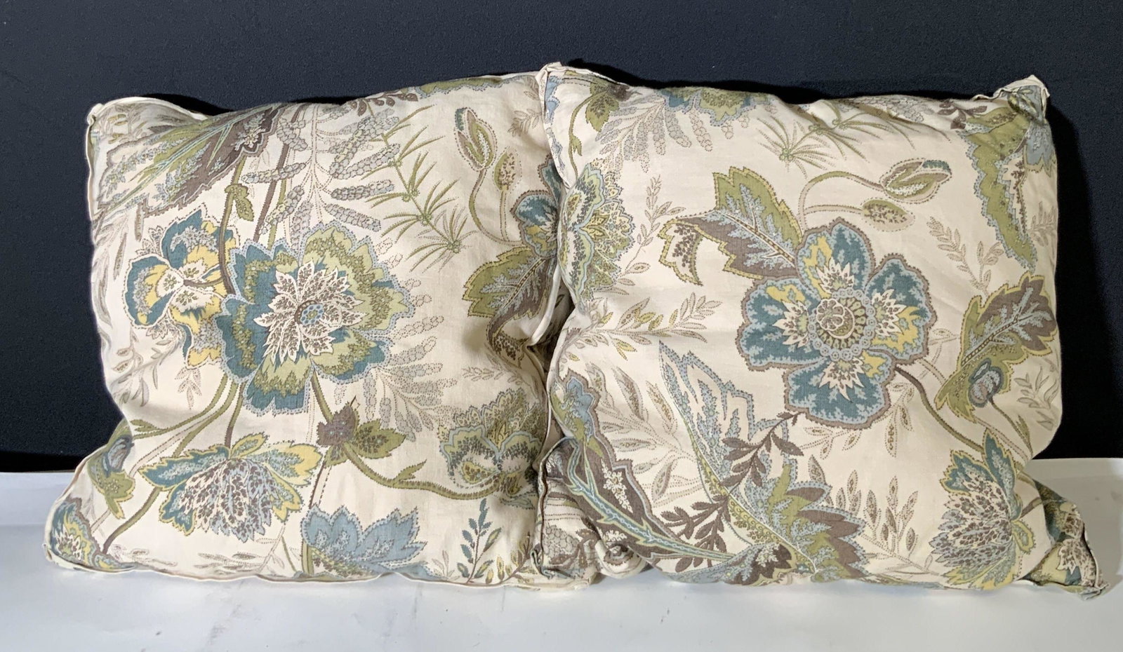 Pair Decorative Floral Linen Throw Pillows: 2 throw pillows with decorative floral designs. Colors are muted earth tones, greens, browns, and yellows. Overall background color is light beige. Fabric in good condition, some staining. One pillow 