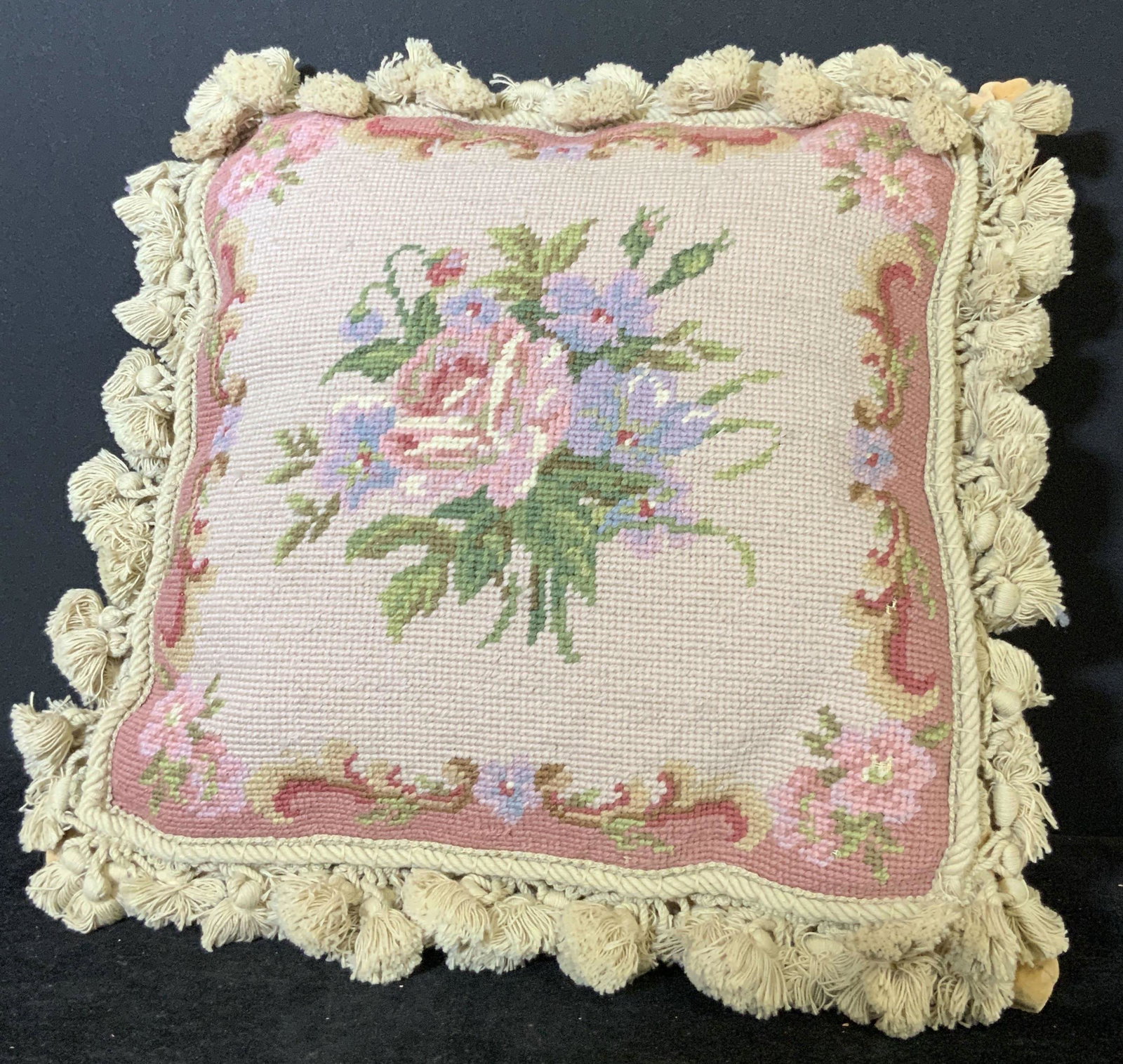 Pink Floral Needlepoint Tasseled Pillow: Needlepoint throw pillow with pink & purple floral designs. Tasseled trimming along all edges. Underside soft textile. One zipper. Approx. 13.5 x 13.5 in. Throw pillow, decorative pillow, floral pillo