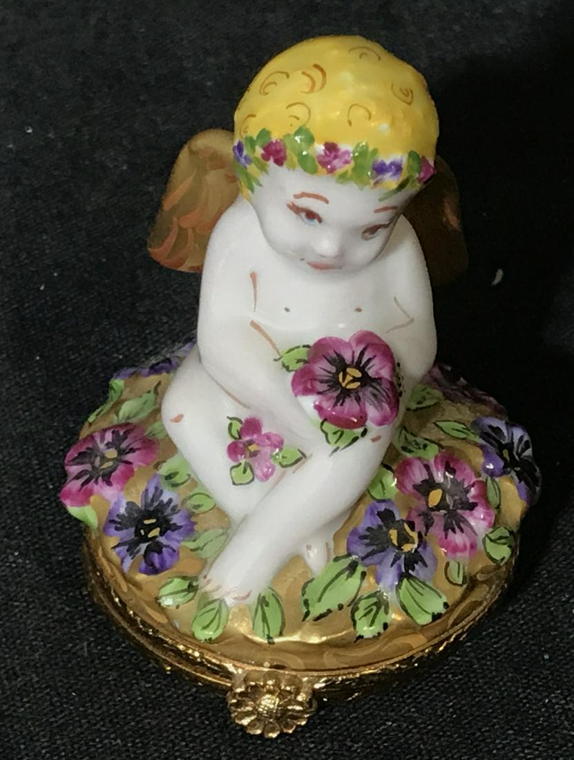 Artoria LIMOGES France Cupid Figural Dish: Artoria Limoges Porcelain Trinket Box, label to underside reads ‘Artoria Limoges Peint Main Made in France’, box depicts a Cupid seated in a platform of flowers, interior displays a purple flower 