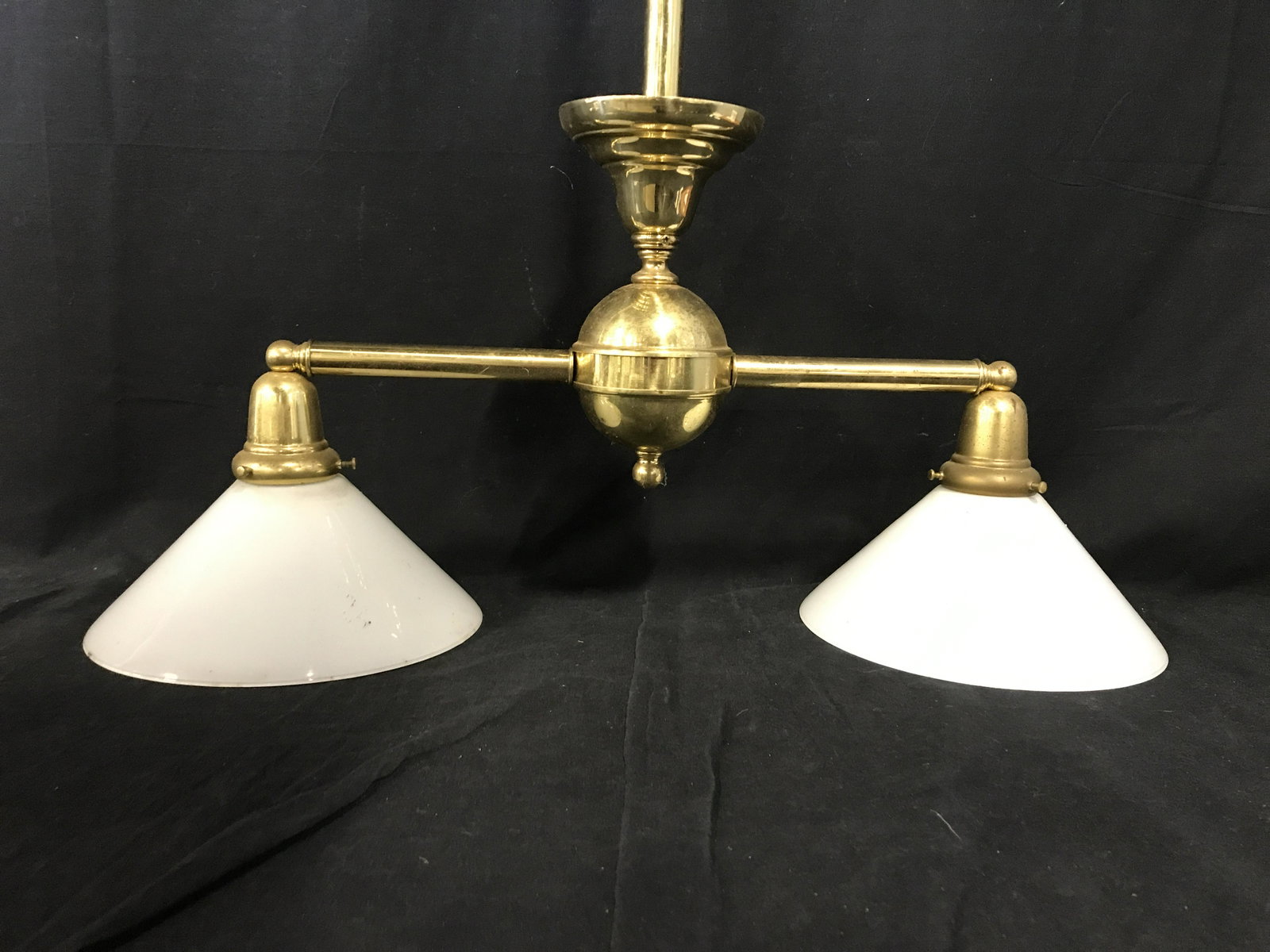 BRASS LIGHT GALLERY Light Fixture: Two light pendant light by BRASS LIGHT GALLERY. Two arms extend and support two glass lamp shades. Measures approx 29 inches H, and 21.25 inches W. Label reads as BRASS LIGHT GALLERY. Wear is consiste