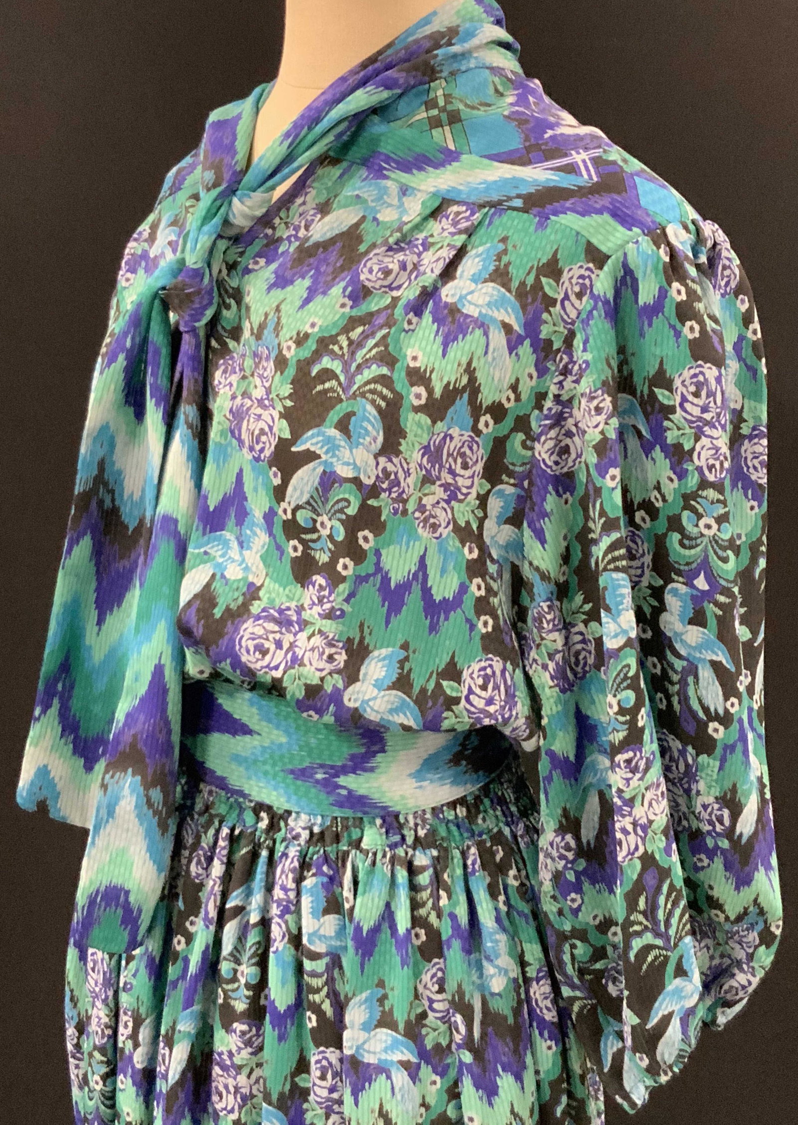 SET 3p MOSAIC Patterned Tie Waist Dress with Vest: Knee length patterned dress. Colors include blues, greens, and deep purples. Floral designs throughout. Dress has cinched waist and sleeves. Dress has attached tie scarf. Waist tie is separate. Quilte