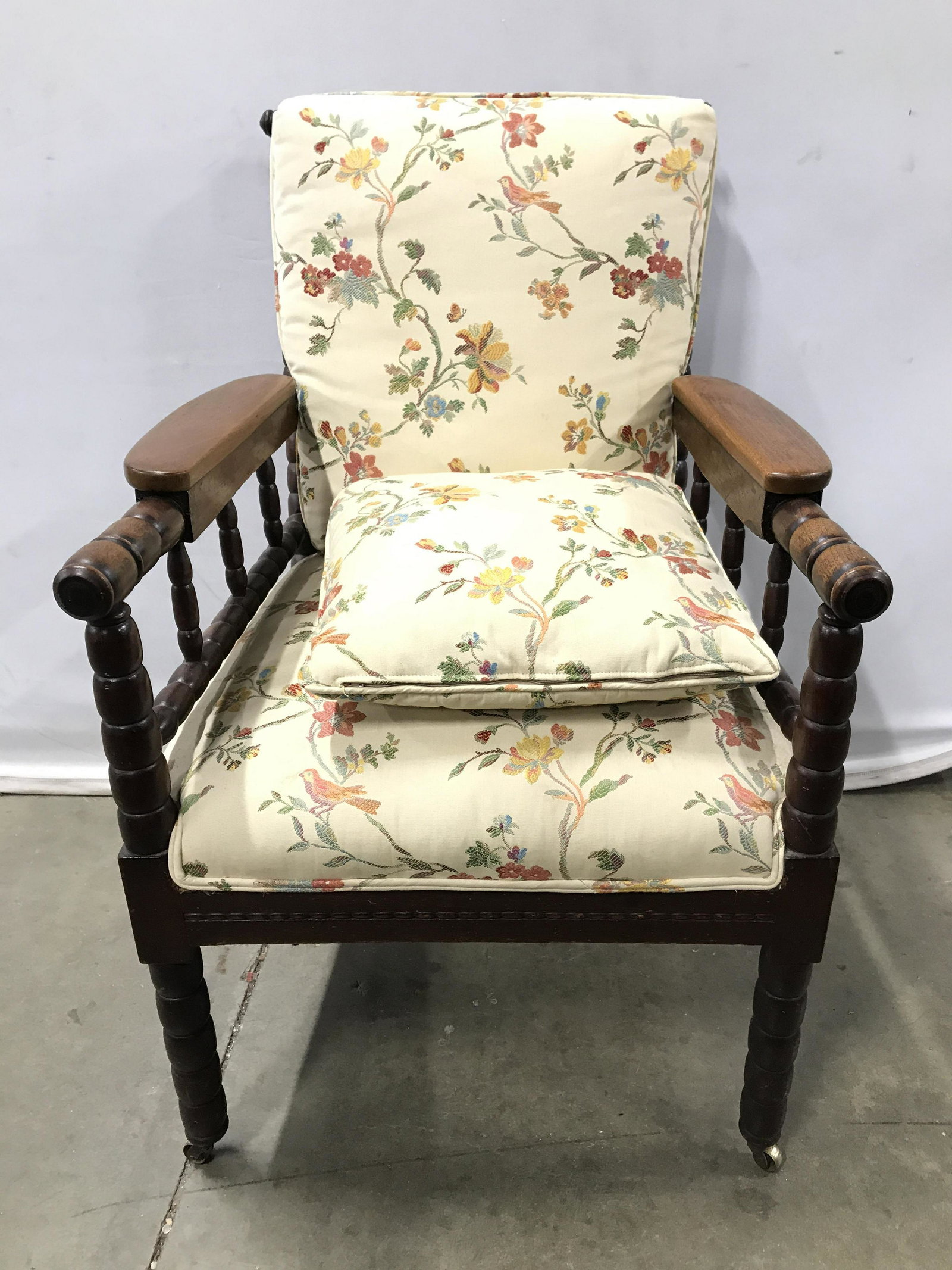 Vintage Carved Wooden Upholstered Chair On Casters: Chair is wooden with carved detail. Chair sits on 4 gold toned casters which appear to be brass. Chair has upholstered seat with double welting at edges. Piece includes matching backrest cushion and p
