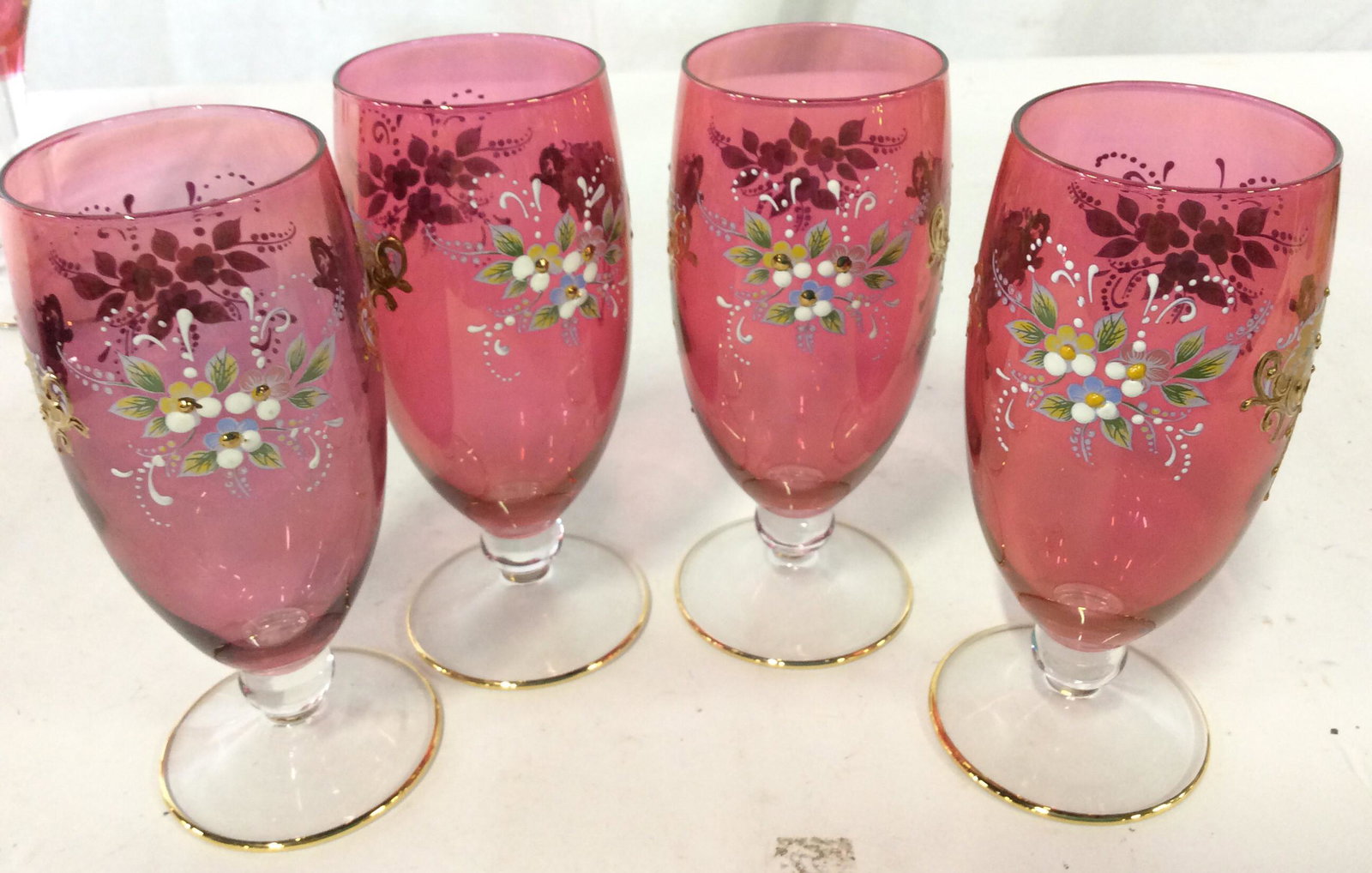 Set 9 Hand Painted Ruby Bohemian Stemware: 4 Tumblers with bases, accents with Gilt rim on base. 5 Trumpet co Matilda glasses also with guilt Base rim, Ht 6.5 in, diameter 3.25 in. All hand painted CRYSTAL. Crystalware, Stemware, Cocktail Glas
