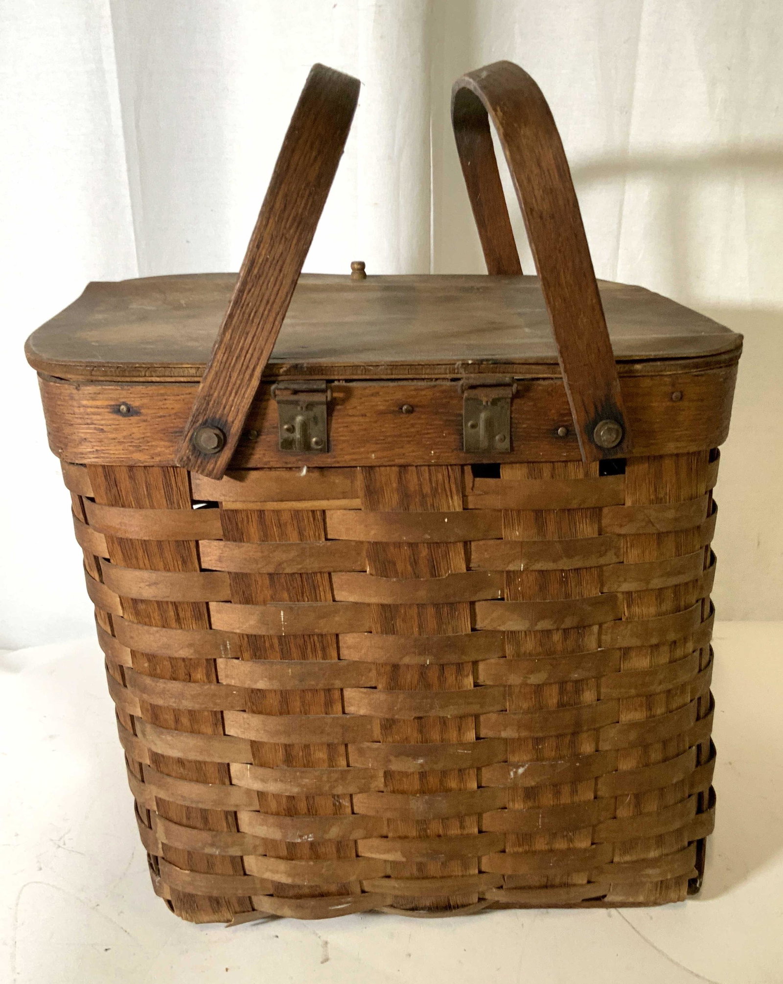 Antique Handmade Wicker Basket with Handles: Handmade basket with hammered rivet nails, swivel handles, hinged top. Deep basket at 12.5 in. Width app 13 in. Depth app 11 in. Ware to lower corners and to bottom, consistent with age and exposure. 