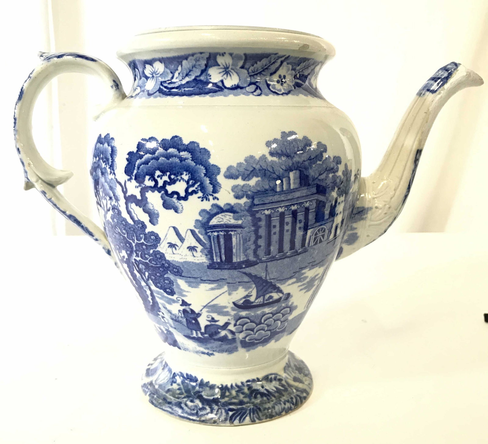 Antique Porcelain Coffee Pot: Coffee pot is porcelain and antique. Piece is white with blue toned floral, leaf, vine and landscape detail. Piece has c scroll style handle. Piece measures approximately 8.5 inches tall 11 inches wid
