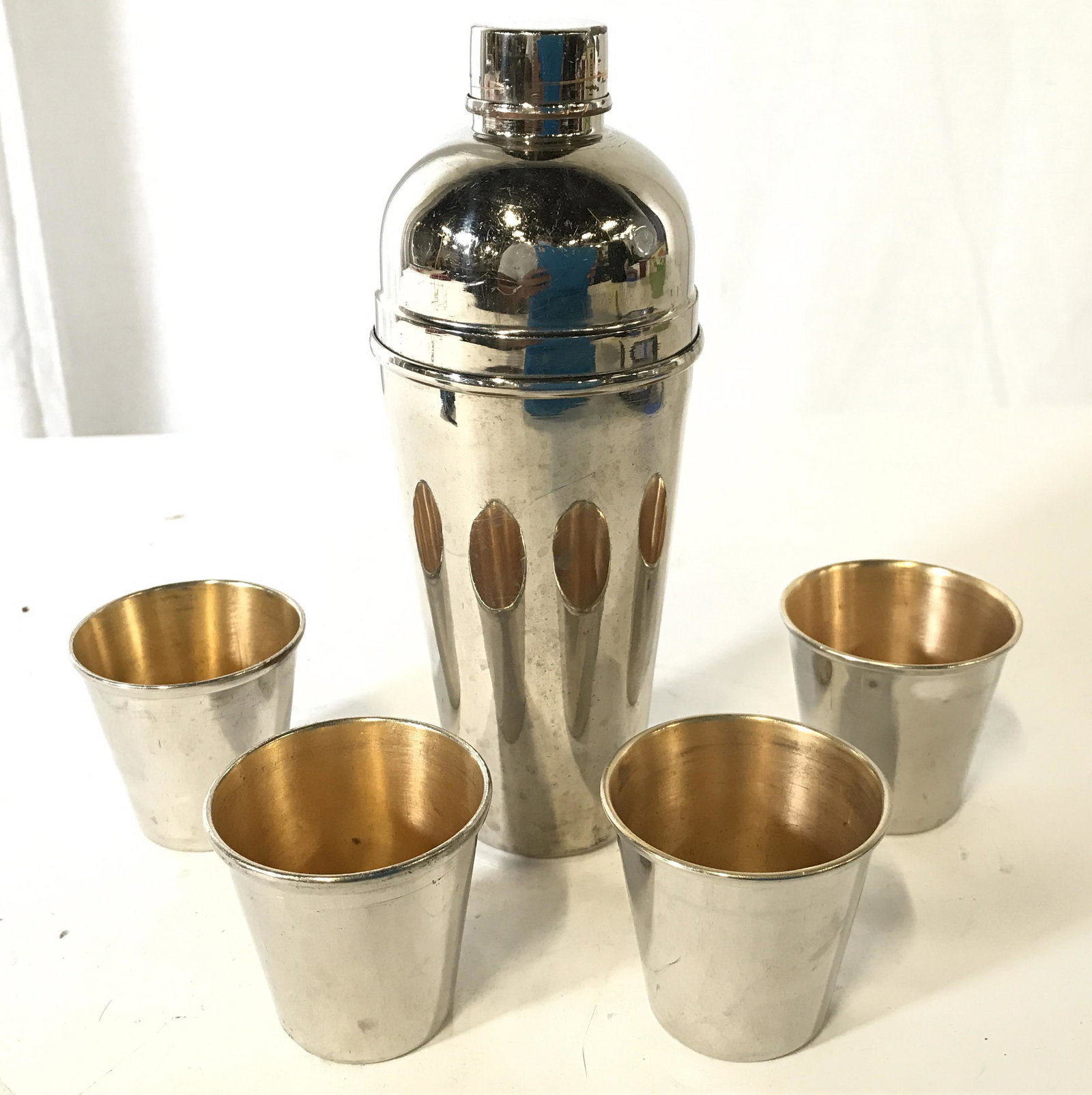 Lot 5 BOBBY PRODUCTS Cocktail Shaker & Cups: Lot includes 1 cocktail shaker and 4 metal cups. Undersides of cups are marked BOBBY PRODUCTS MADE IN CANADA. Shaker measures approximately 7.5 inches tall 3 inches wide. Barware, bar accessories, coc