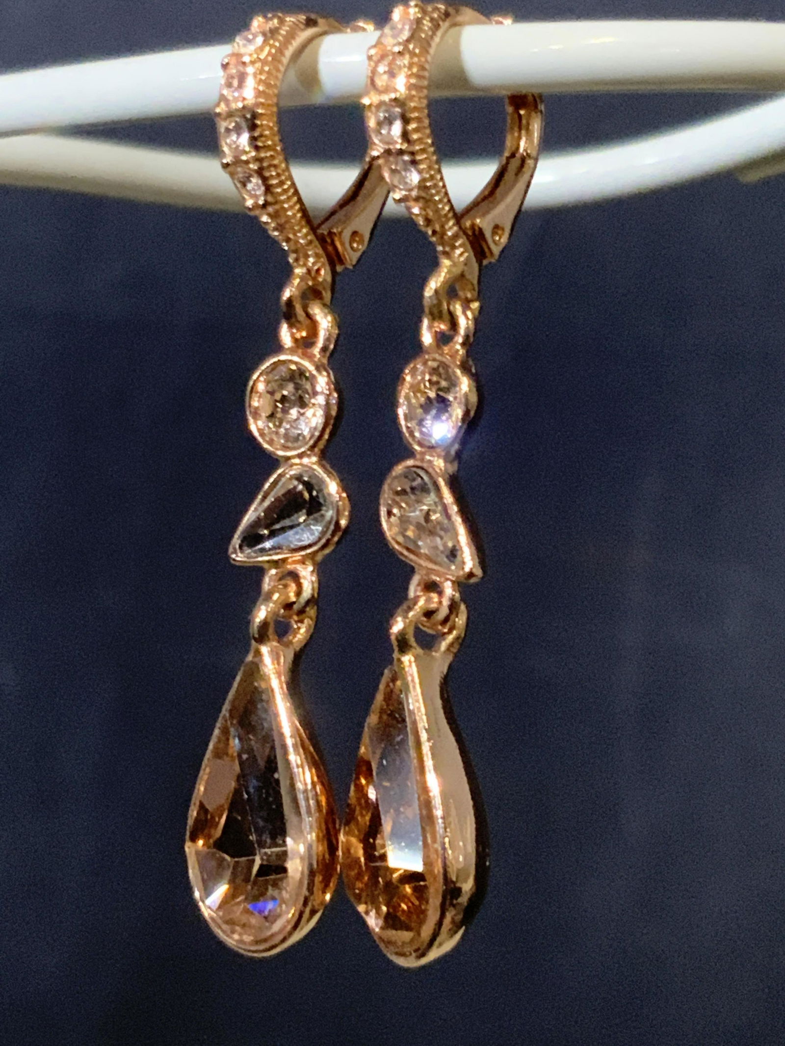 signed GIVENCHY Dangle Crystal Earrings: lever back style with crystals hugging ear draping in a fashionable rose gold toned metal. Just over a 1.5 in dangle, pear shape stone in bezel setting resembling morganite. GIVENCHY stamped on backsi