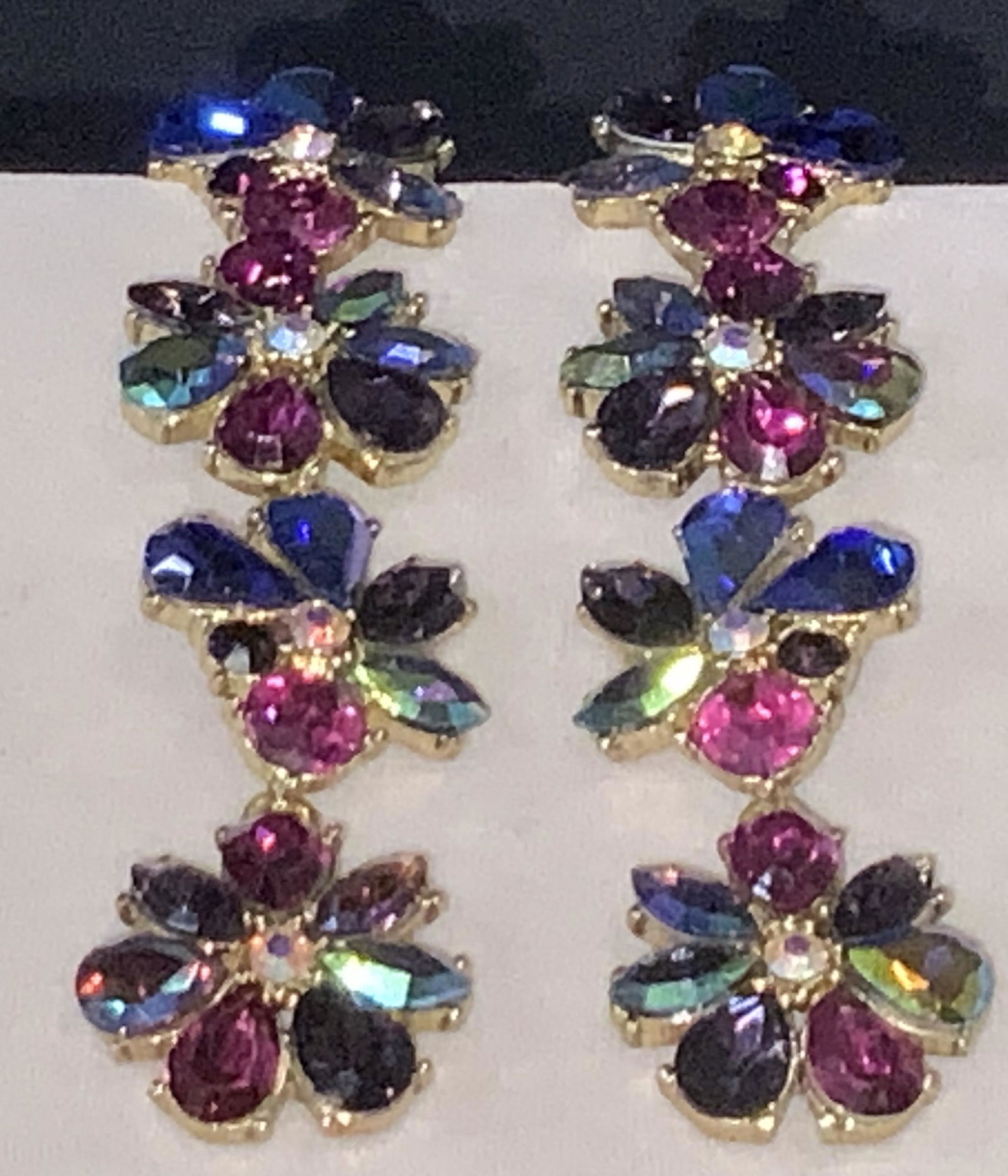 BETSY JOHNSON Floral Dangle Costume Earrings: almost 4 in. Betsy Johnson earrings. Has post and disc backing. 4 clusters of multi chrome flowers , ab crystal rhinestones. bezel set, app 3/4 in wide. Off set using gold tone metal. One rhinestone n
